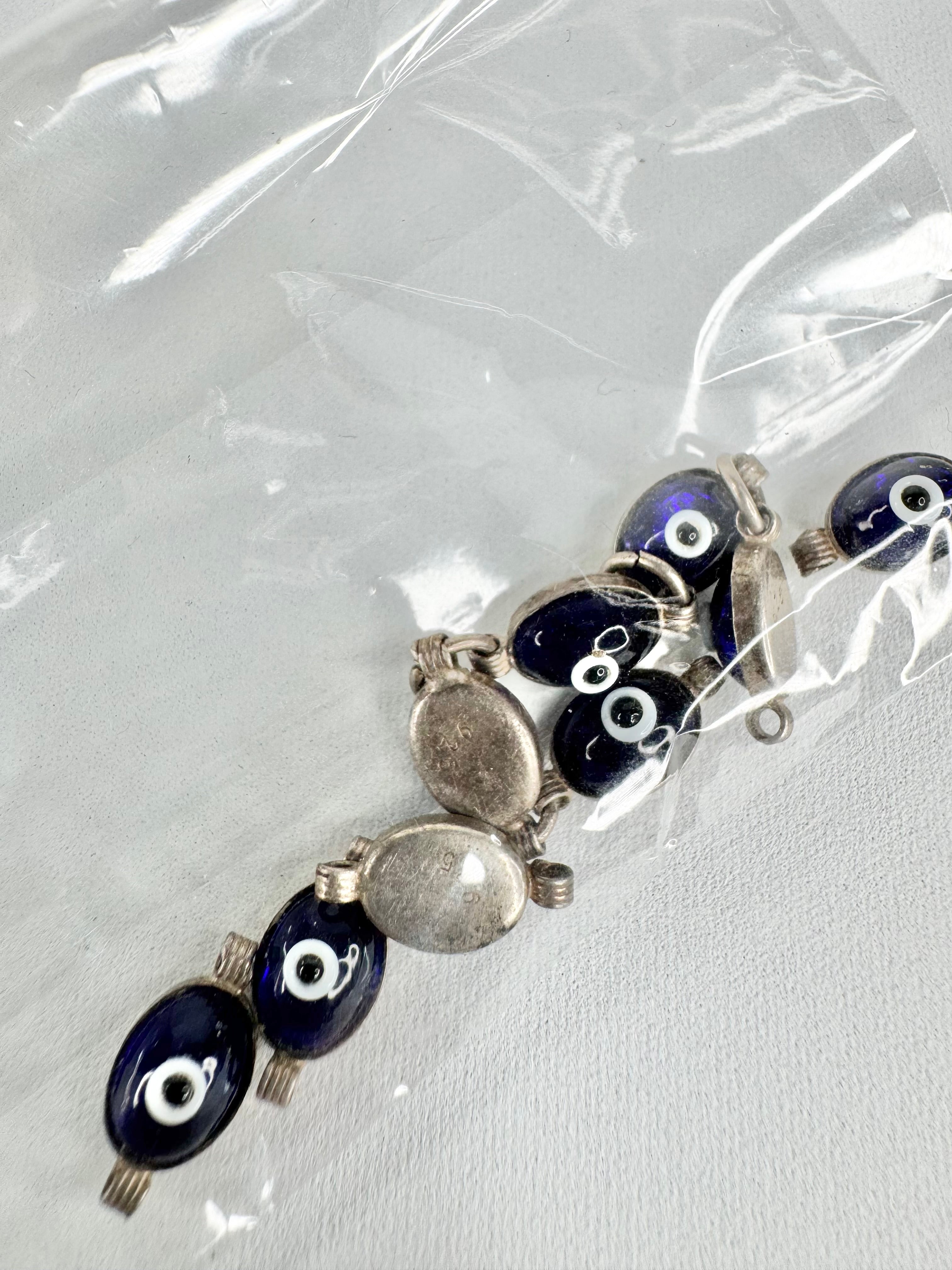Bracelet with blue eye-shaped beads and silver connectors on a clear background