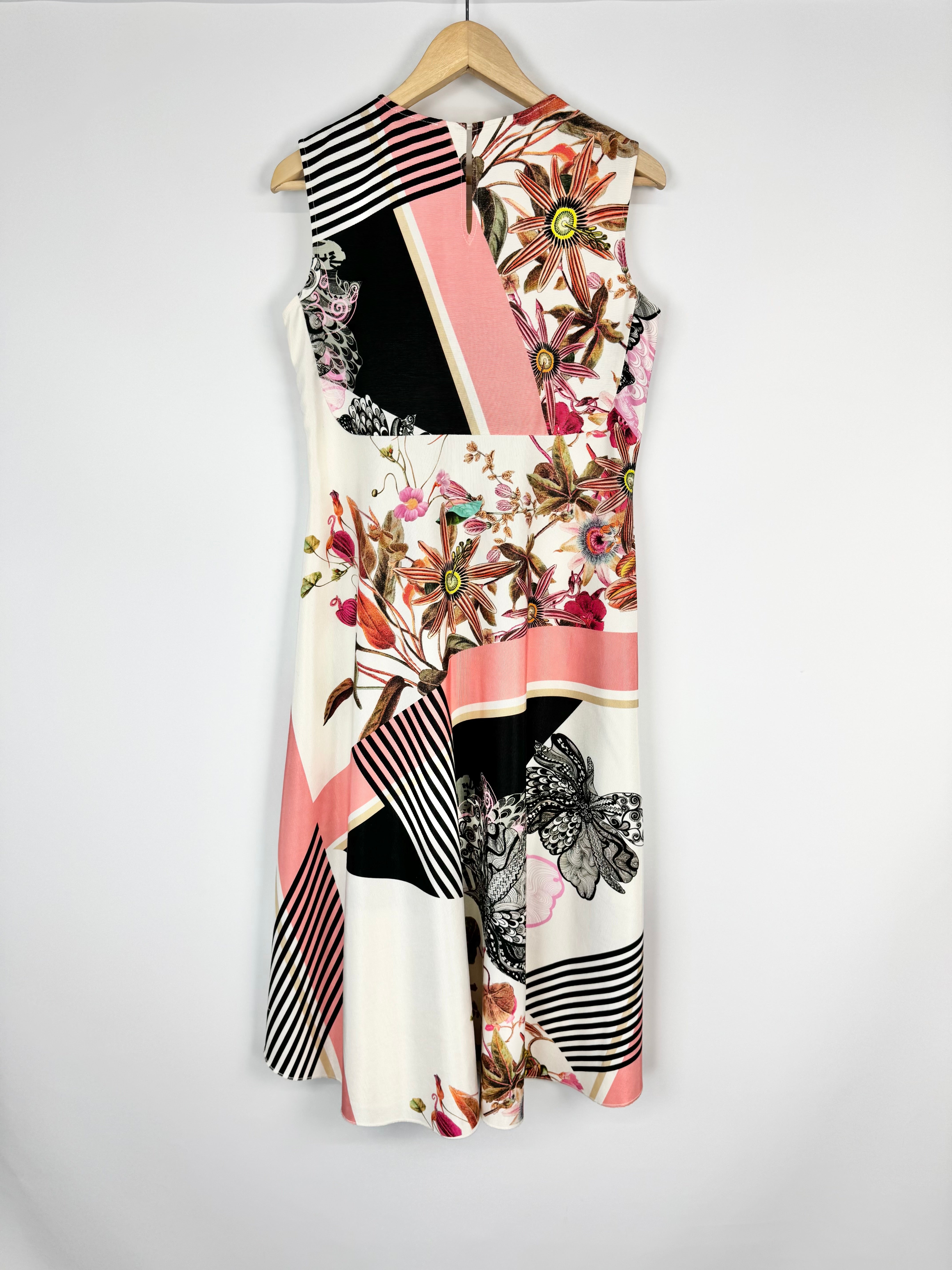 Colorful dress with floral and abstract patterns on a hanger against a white background