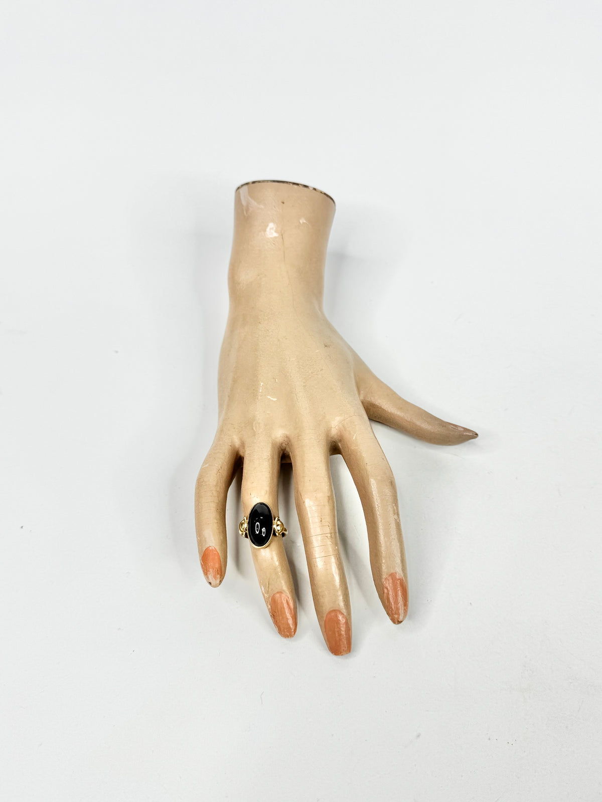 Mannequin hand wearing a ring with a black stone on a white background