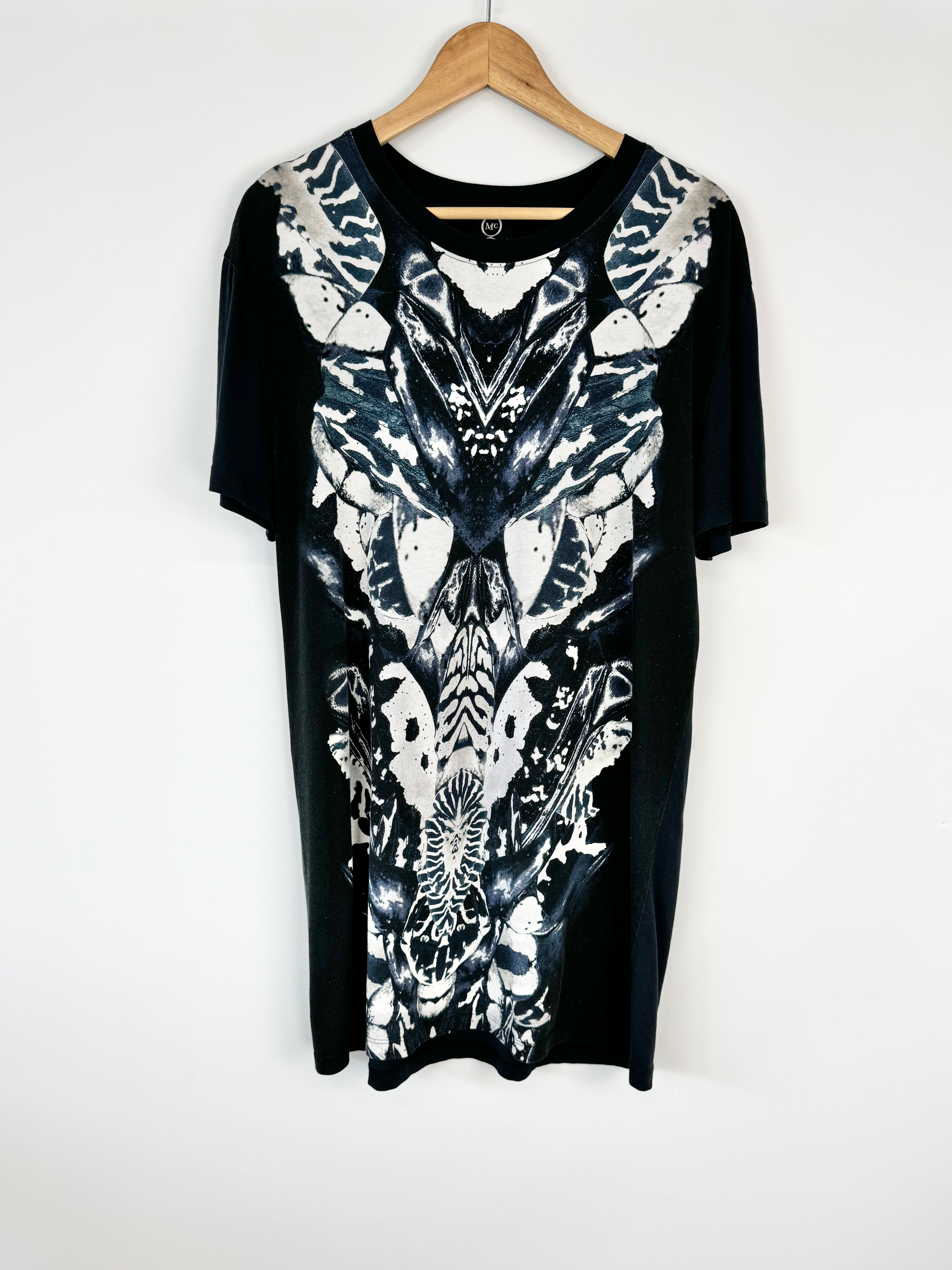 Black dress with white abstract pattern on a hanger against a white background