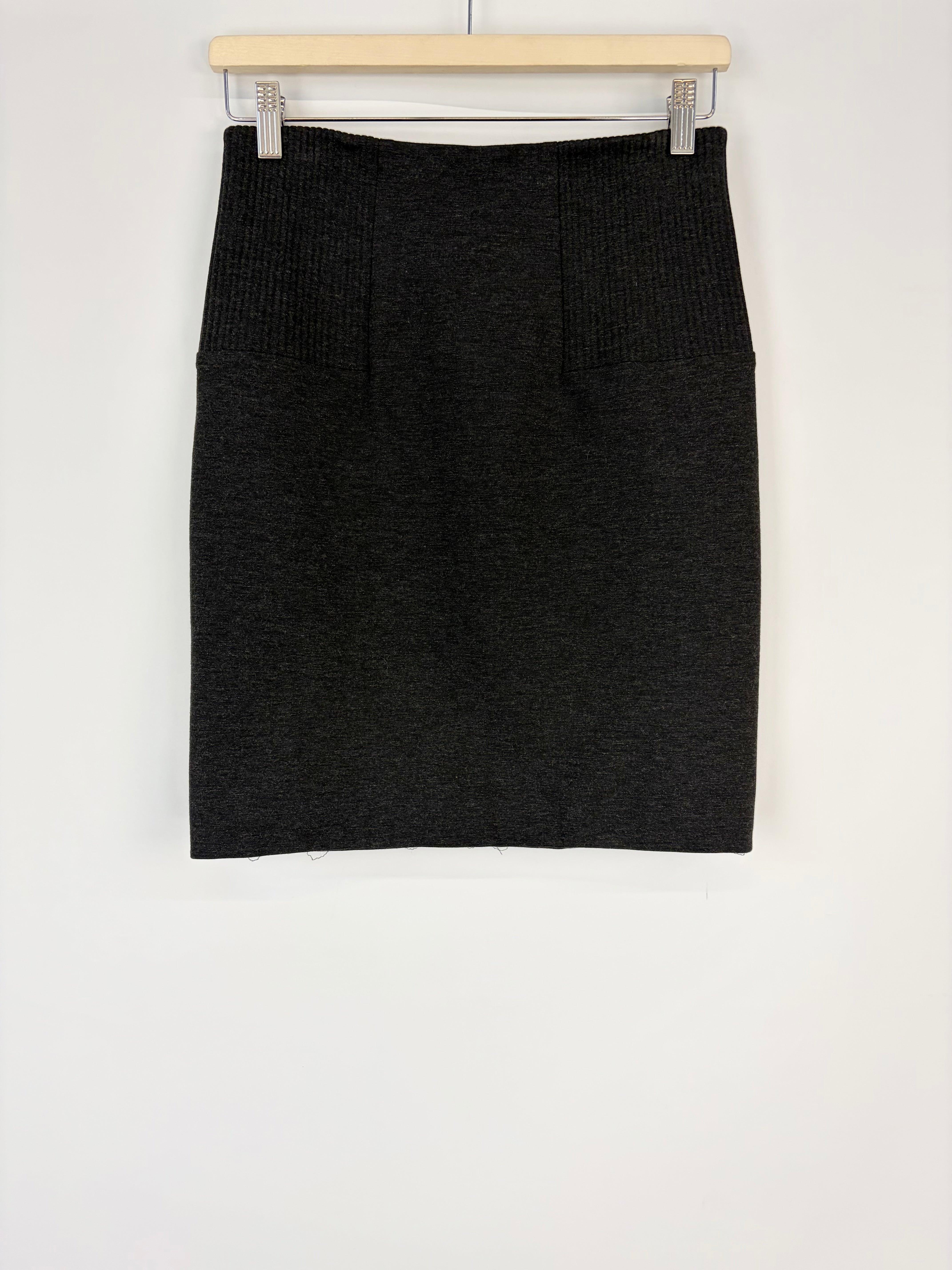 Black knit skirt on a hanger against a white background