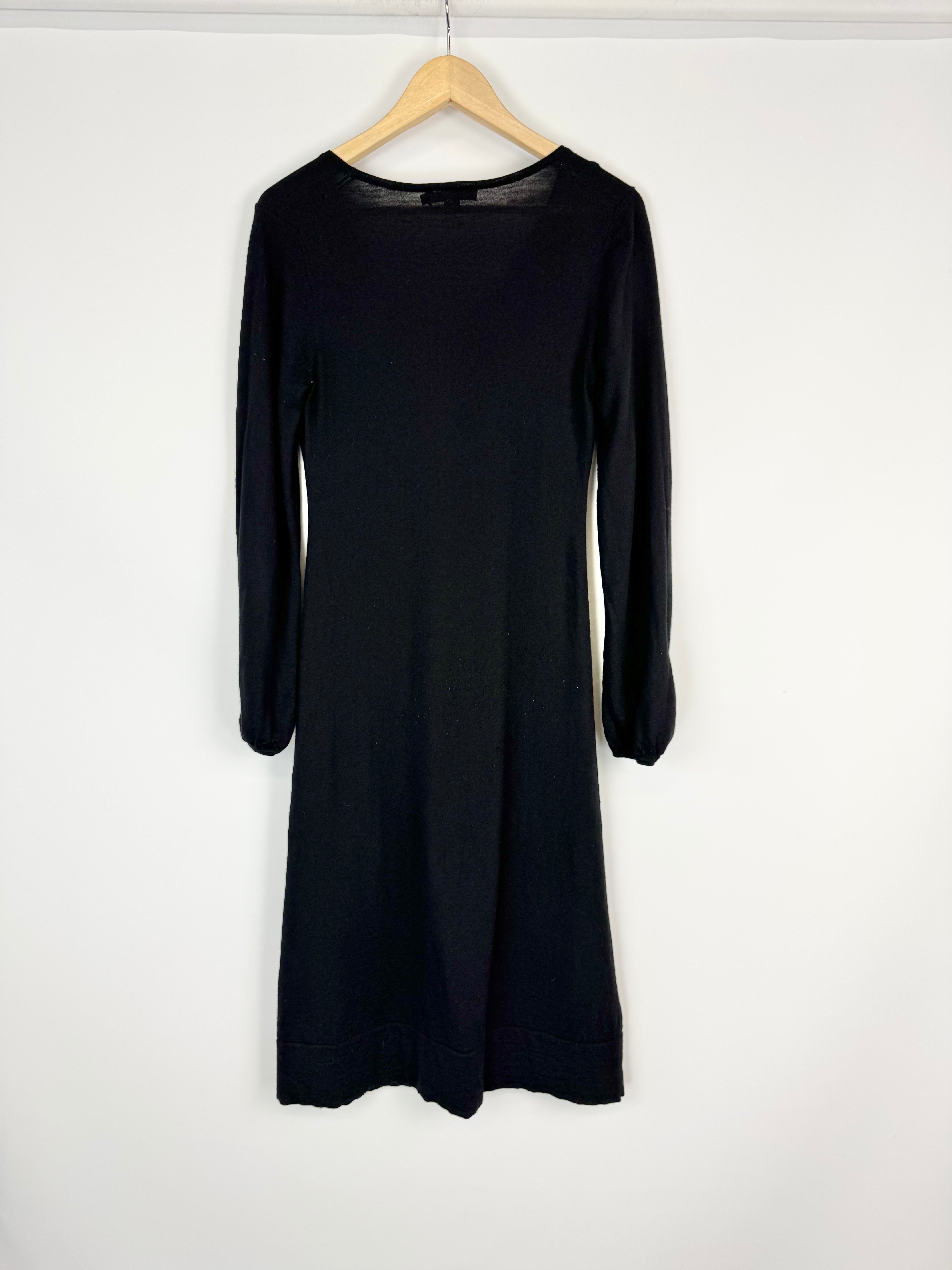 Black dress on a hanger against a white background