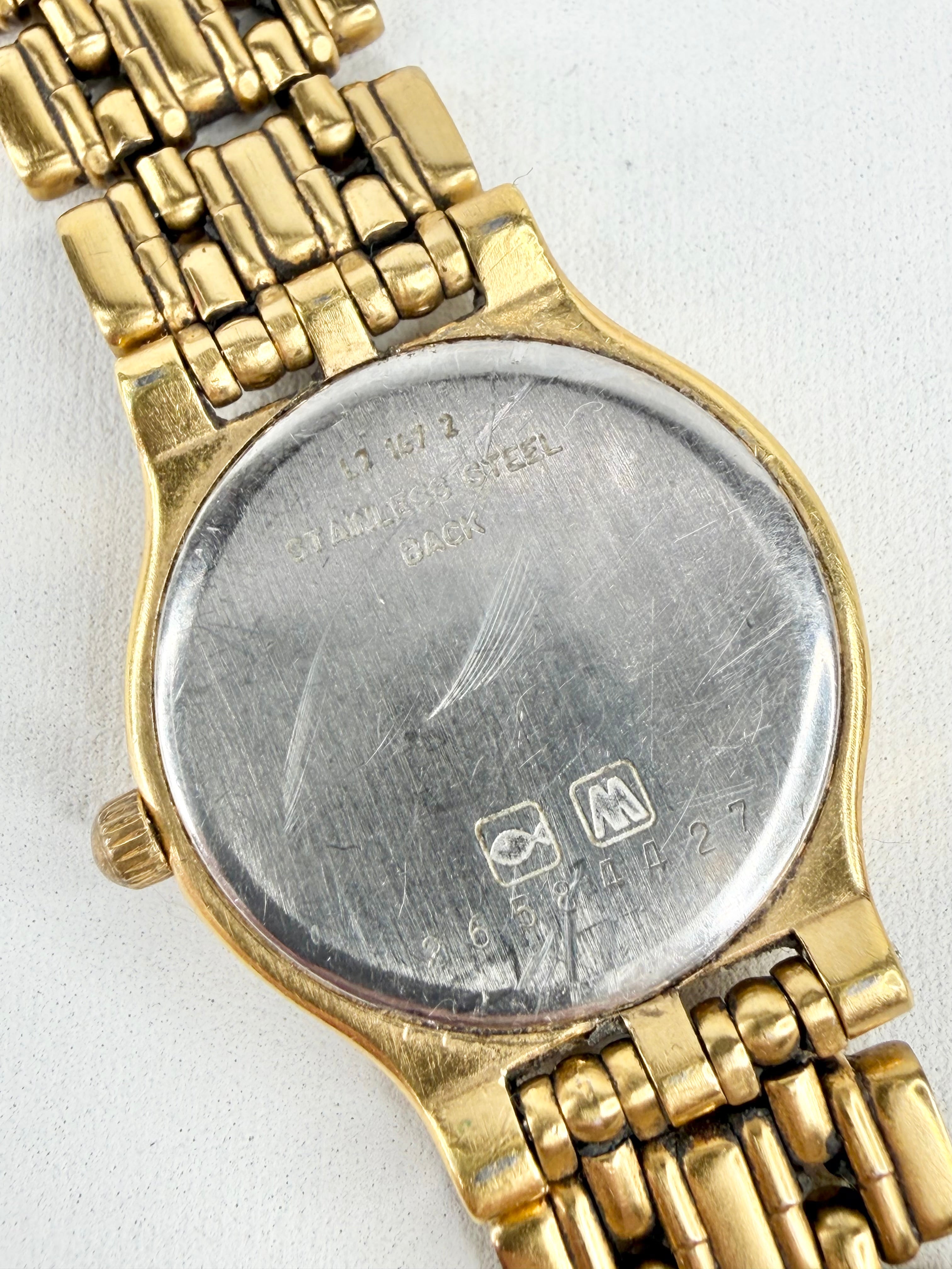Close-up of a gold wristwatch with visible brand name on a white background