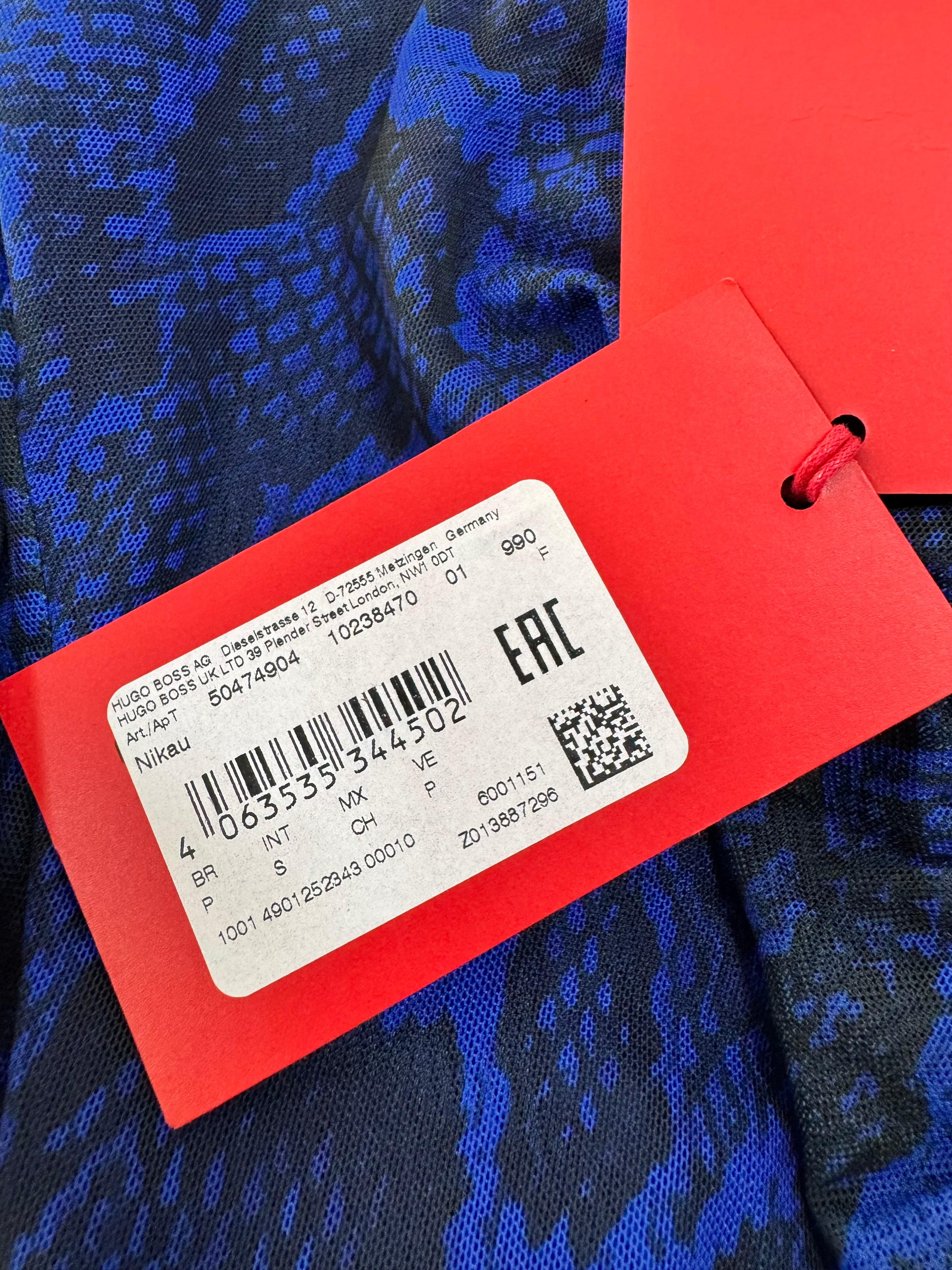 Red tag with a barcode and text on a blue patterned fabric background