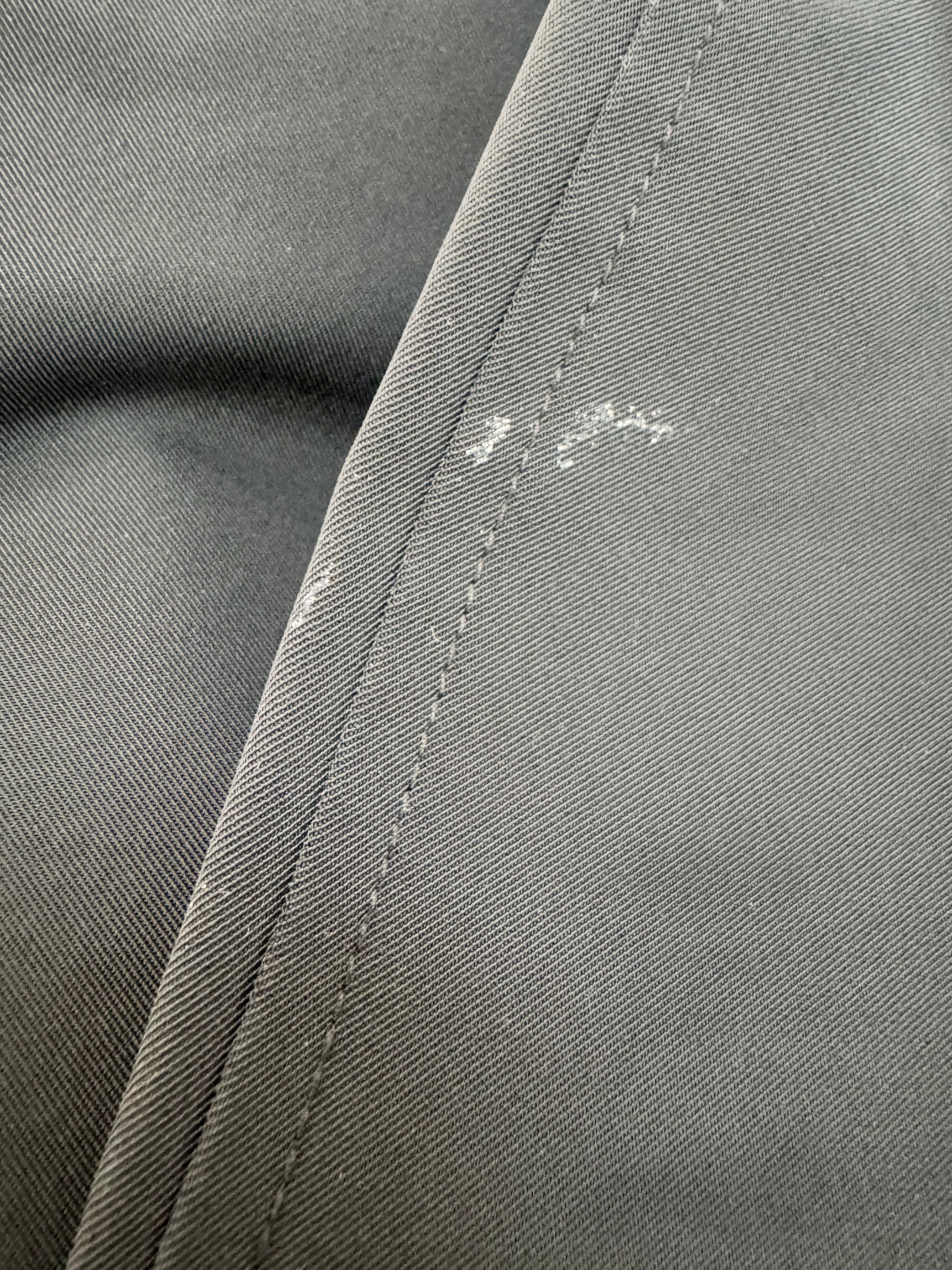 Close-up of gray fabric with a visible stain and seam