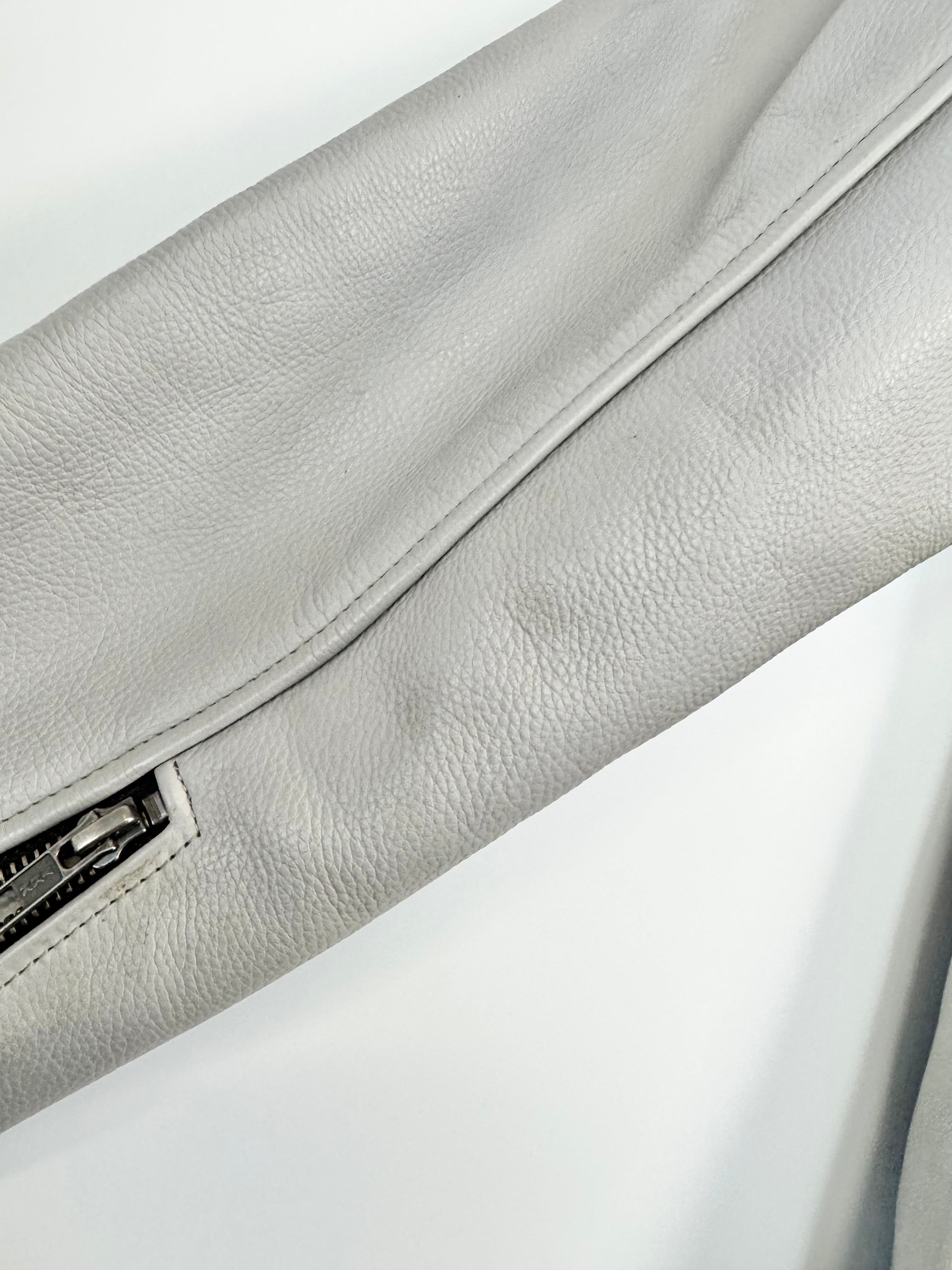 Close-up of a light gray leather bag with a zipper on a white background