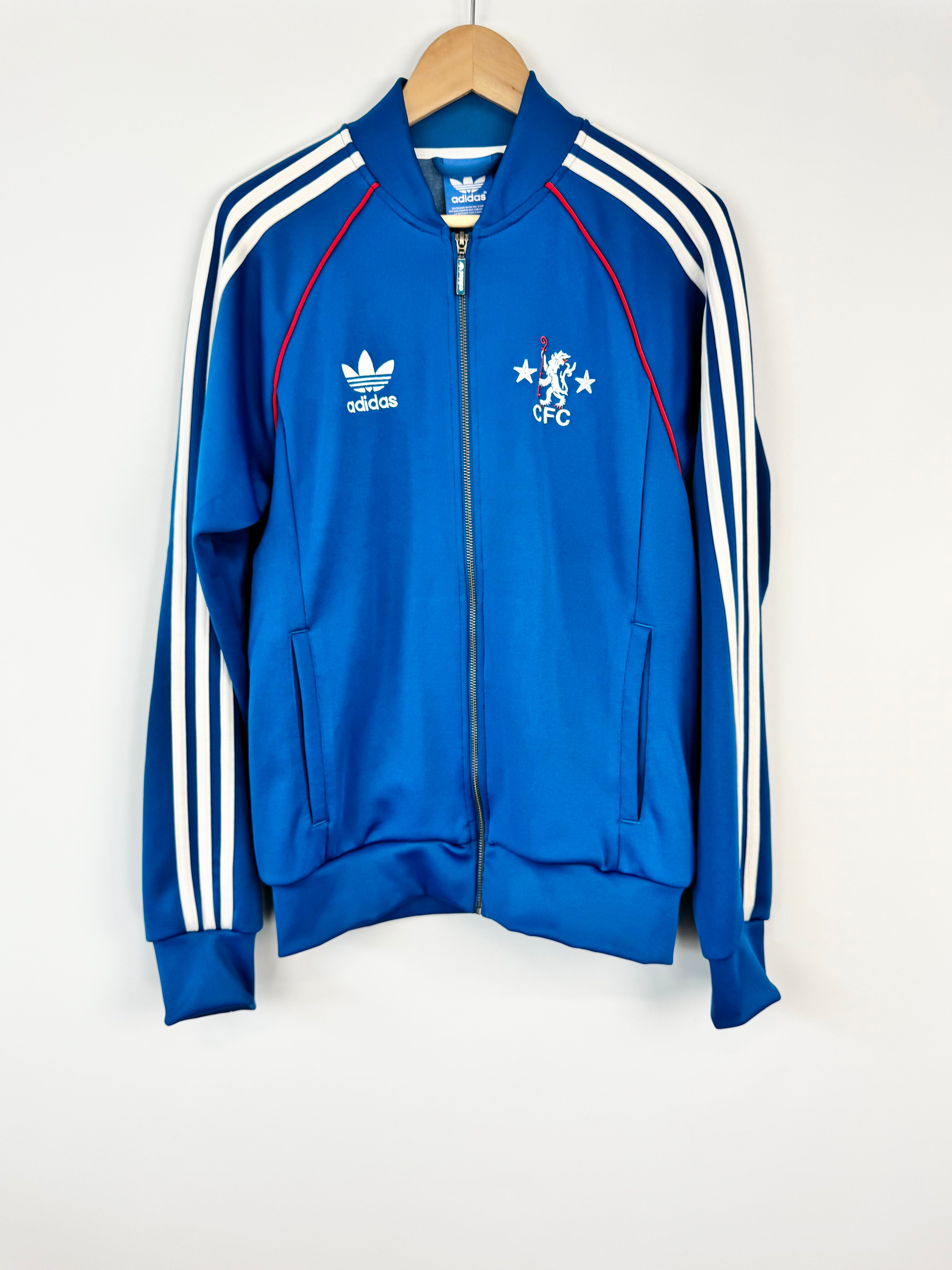 Blue Adidas jacket with white stripes on a hanger against a white background