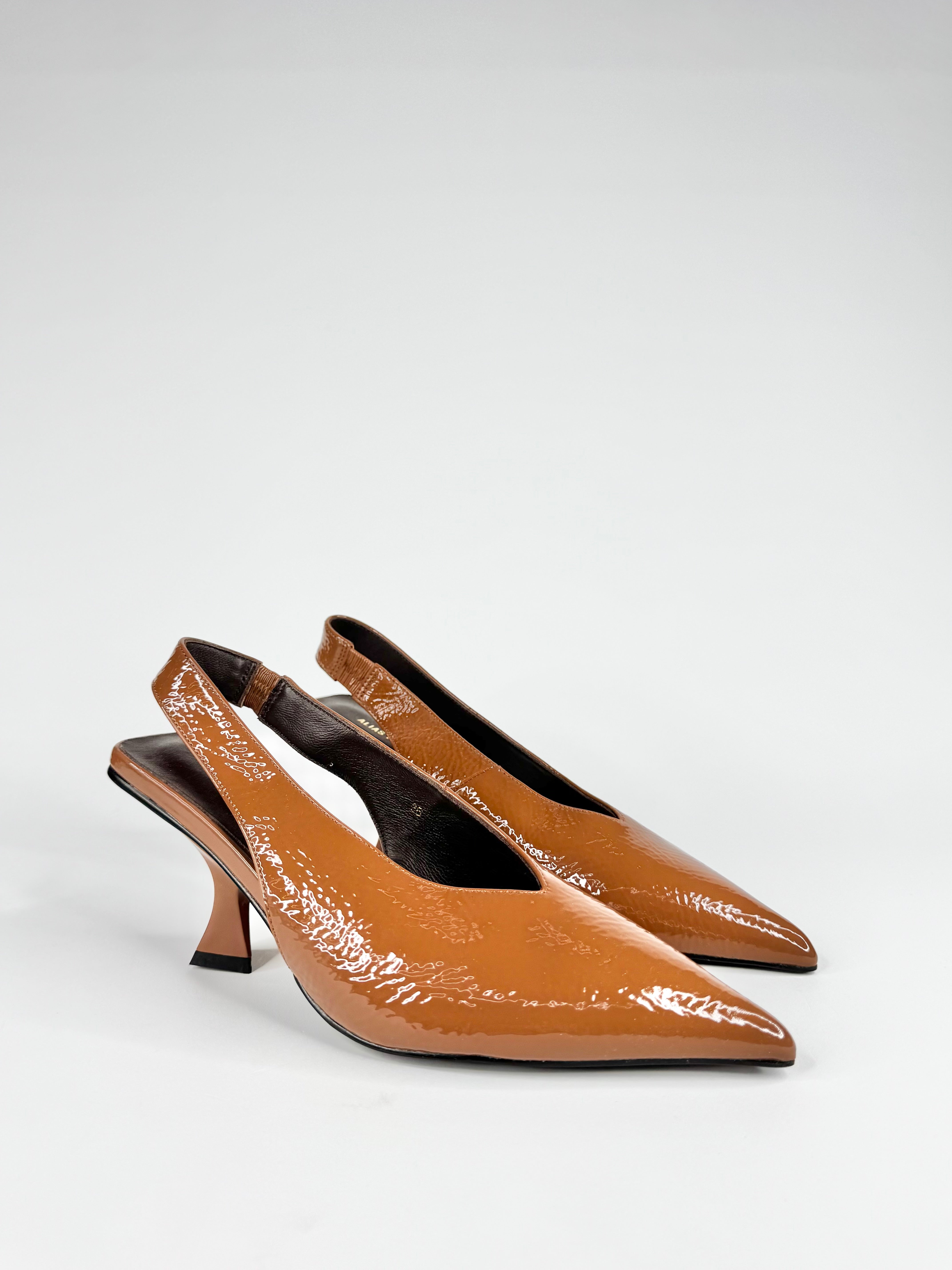 Pair of brown patent leather slingback heels on a white background