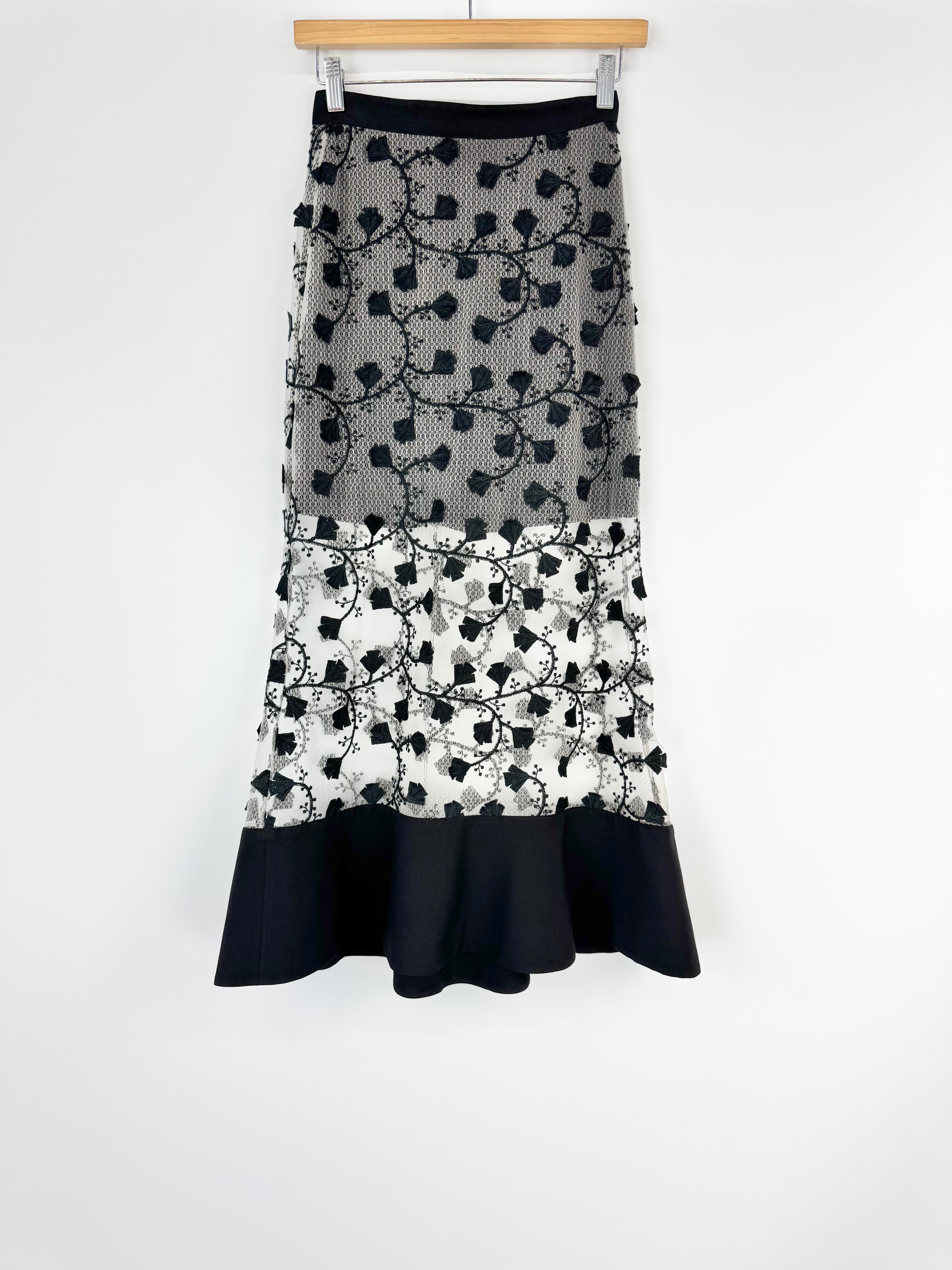 Black and white patterned skirt on a wooden hanger against a white background