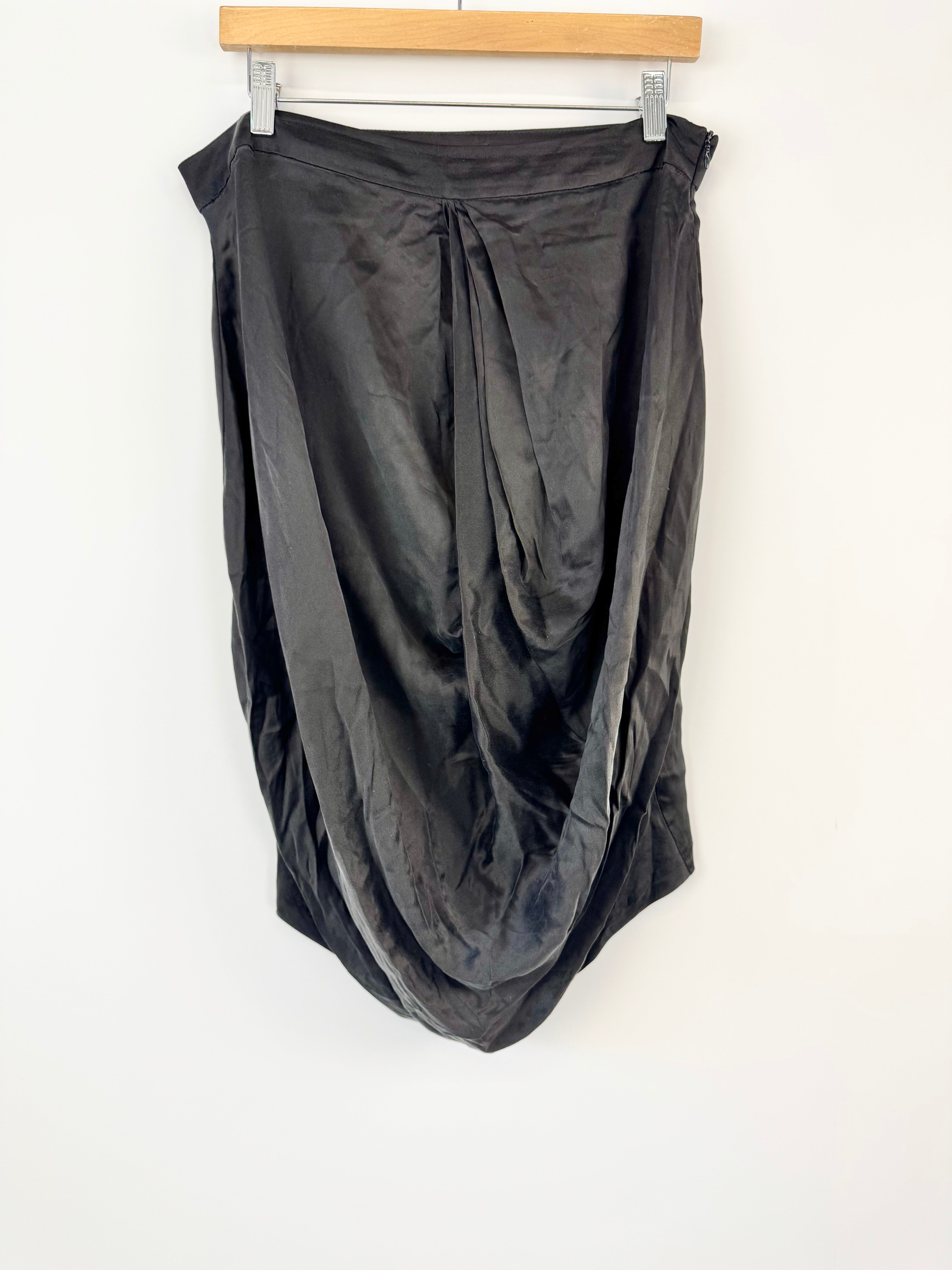 Black draped skirt on a hanger against a white background