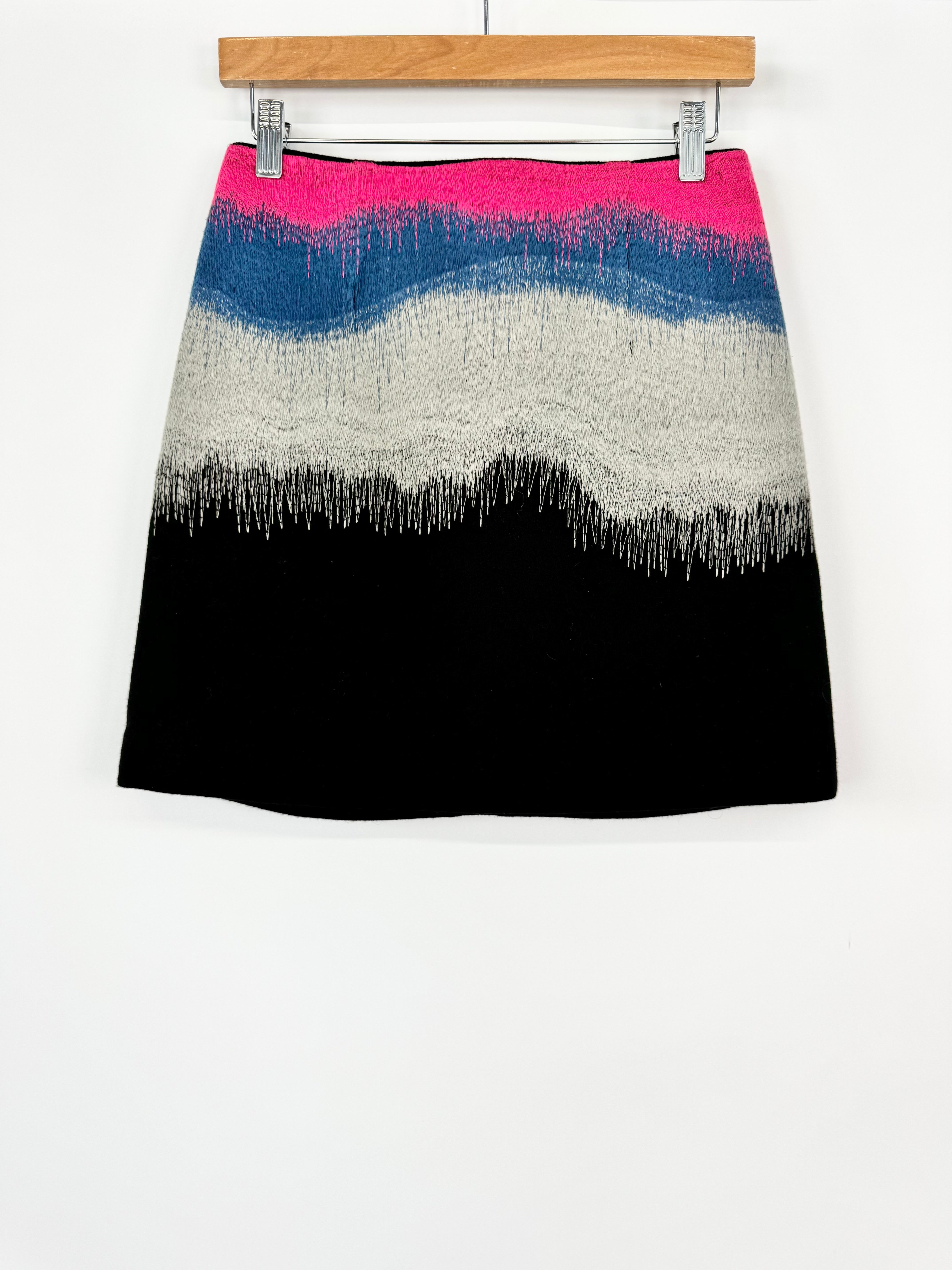 Color-blocked skirt with pink, blue, white, and black gradient on a white background
