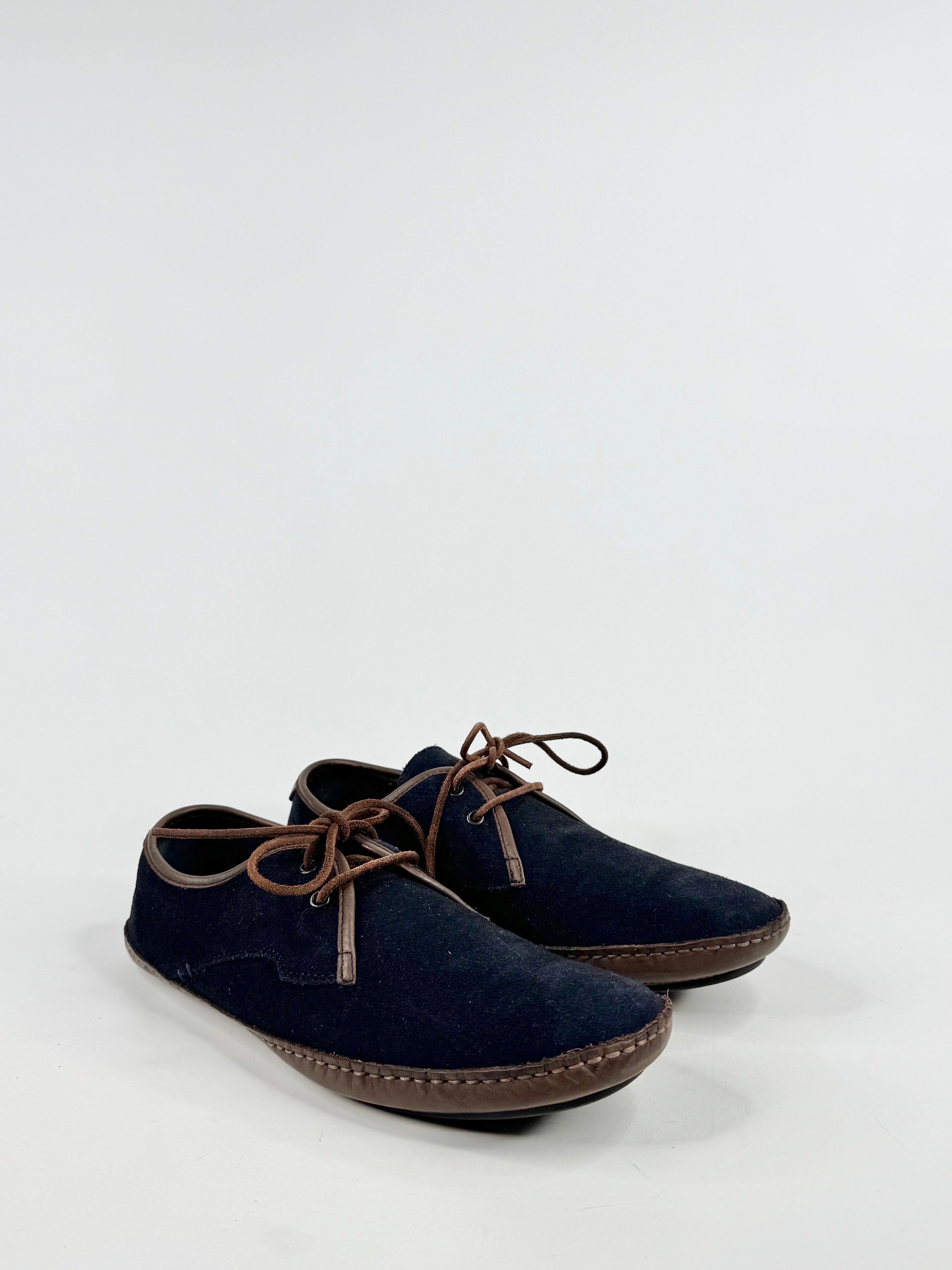 Pair of navy blue shoes with brown laces on a white background