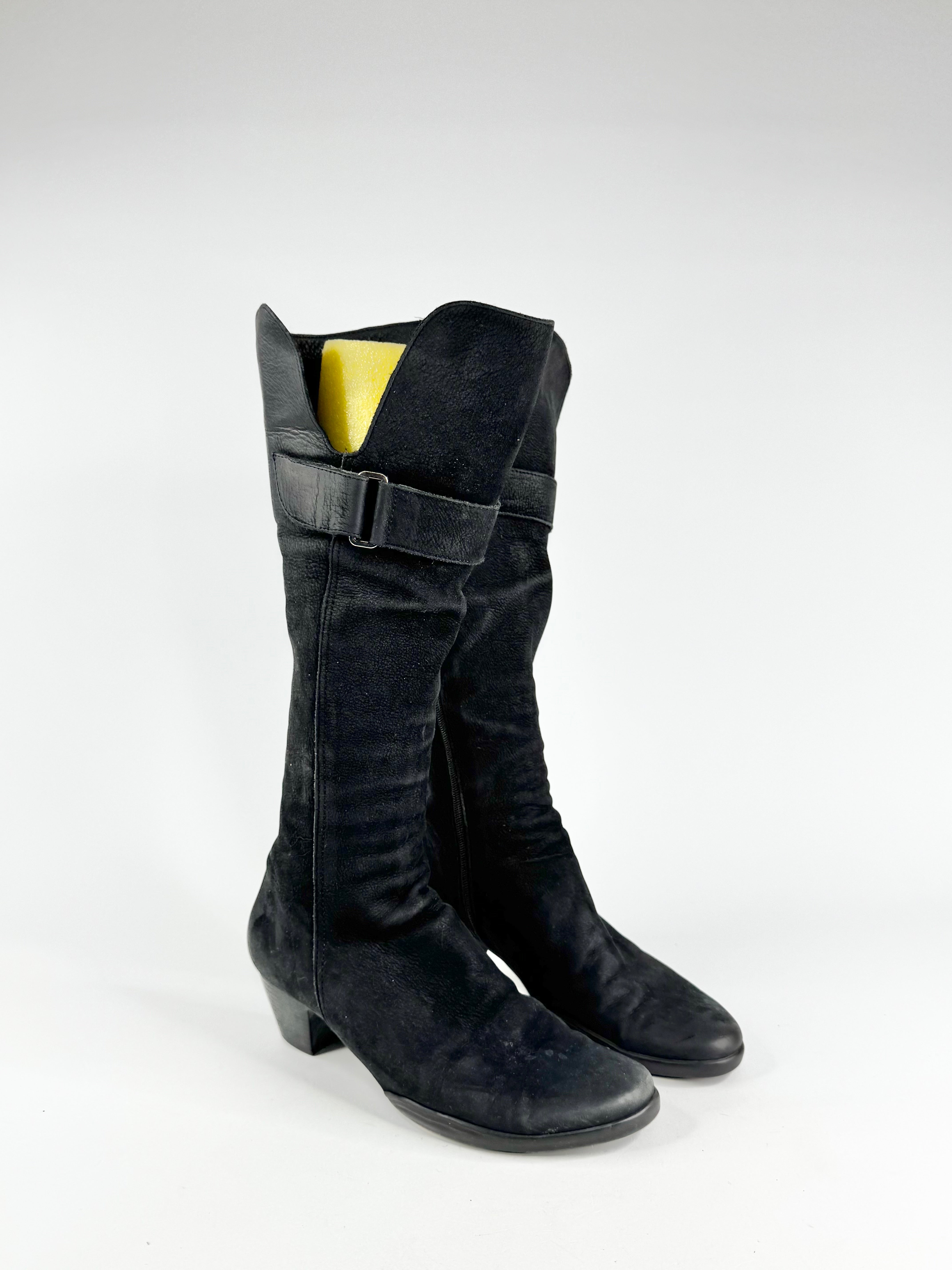 Black knee-high boots with a buckle on a white background