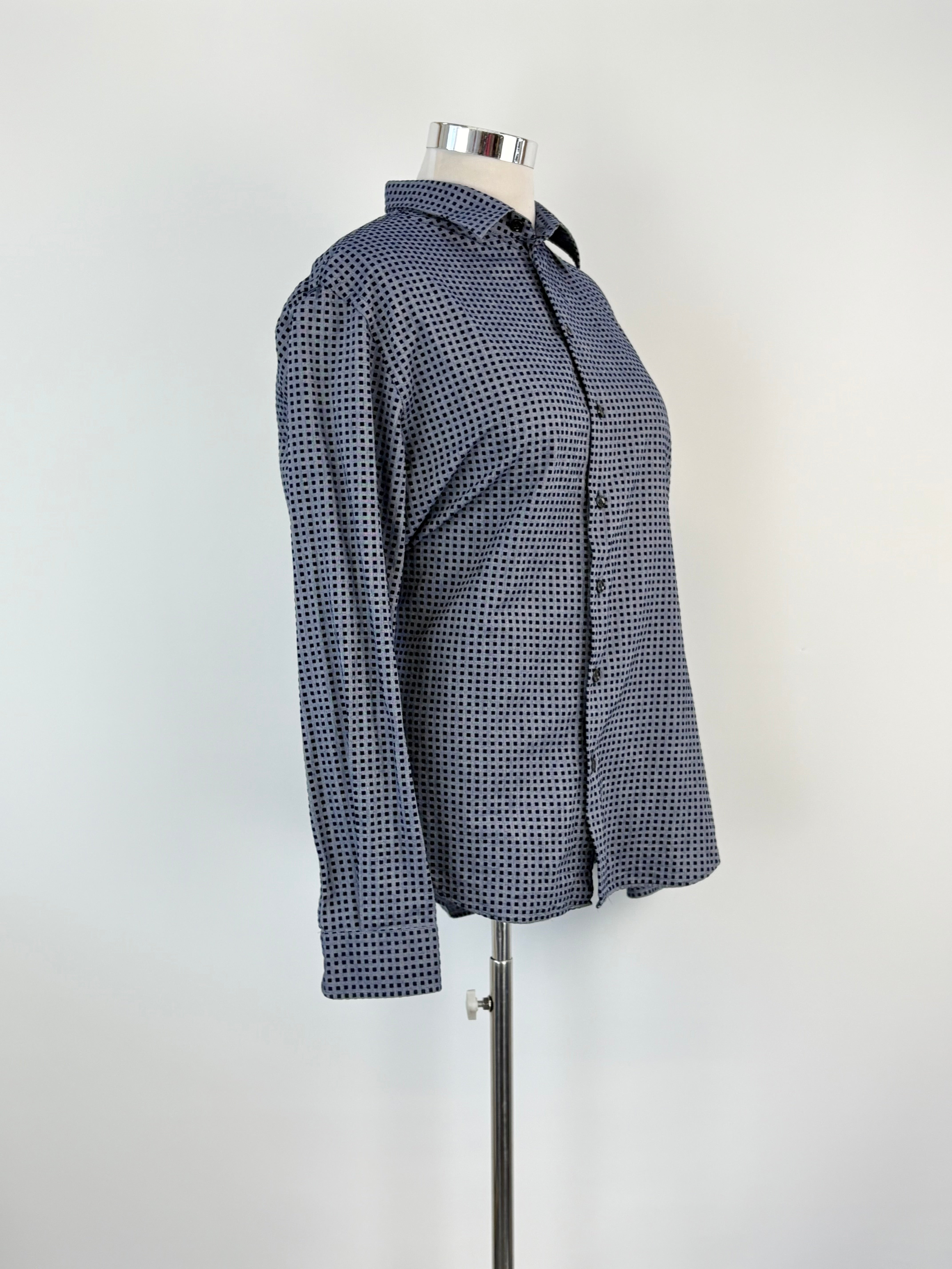 A long sleeve, button-up shirt with a felted square pattern on a pigeon blue base, displayed on a mannequin.