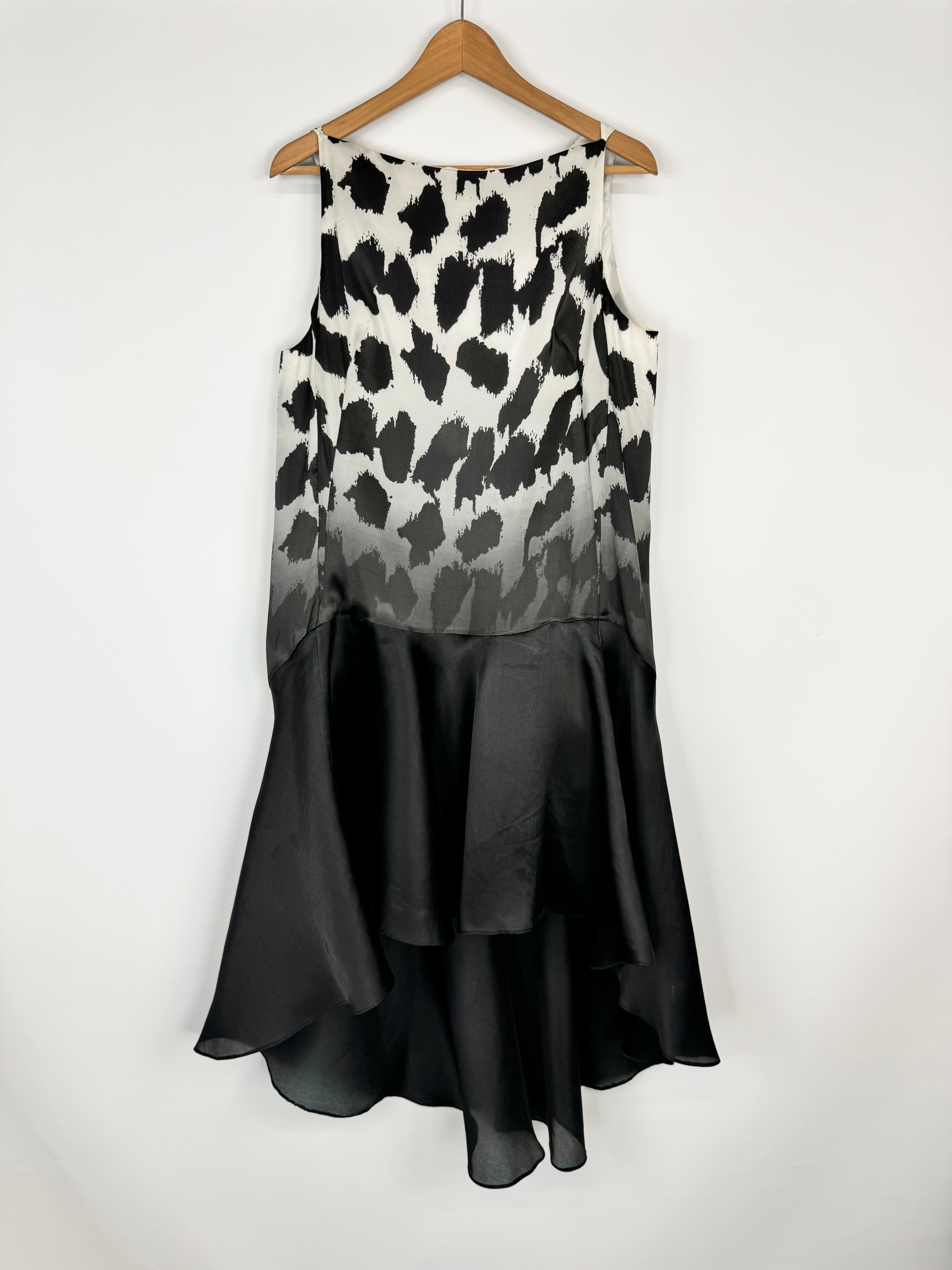 Dress with black and white patterned top and black bottom on a hanger against a white background