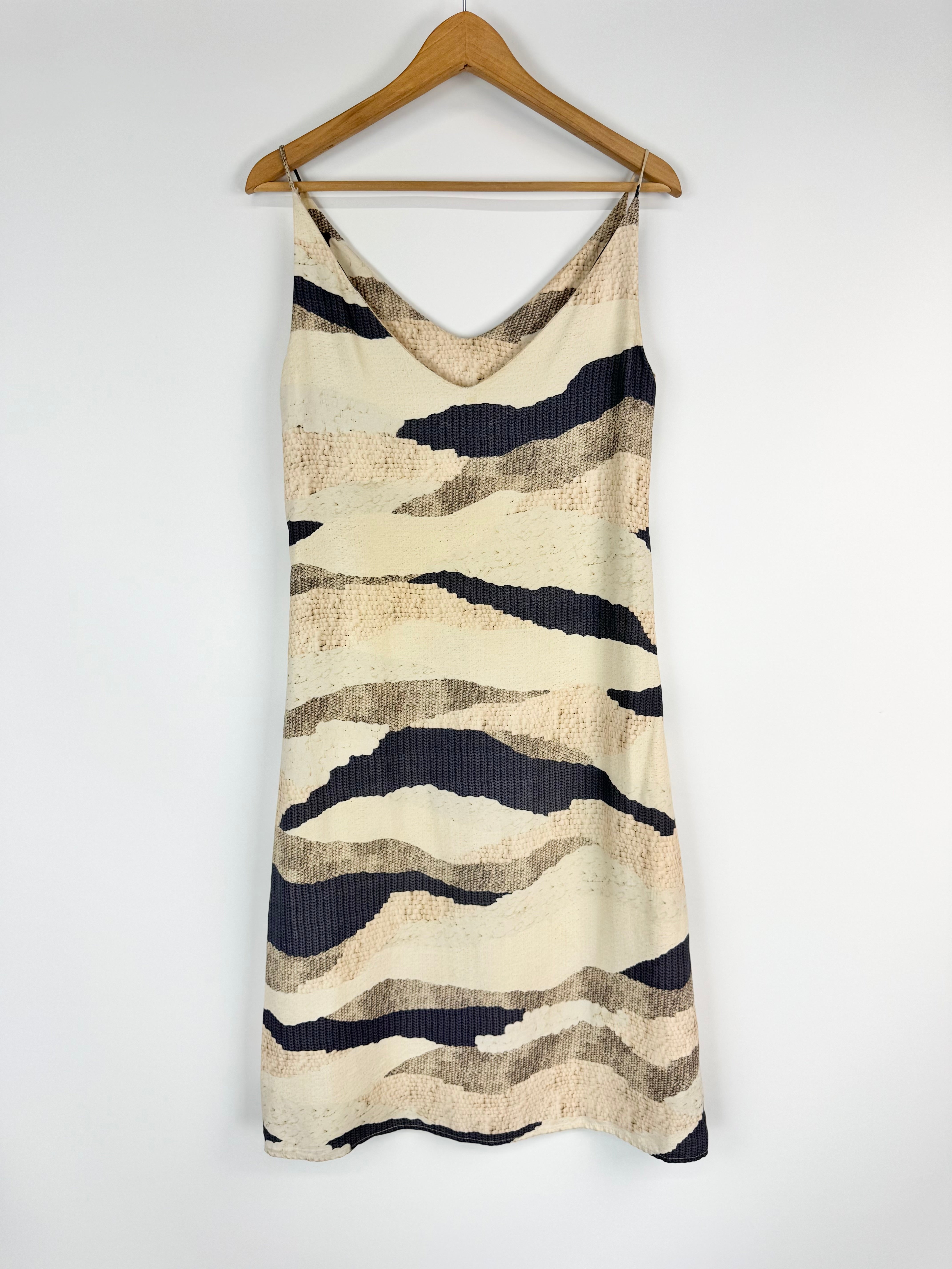 Camouflage-patterned dress on a wooden hanger against a white background