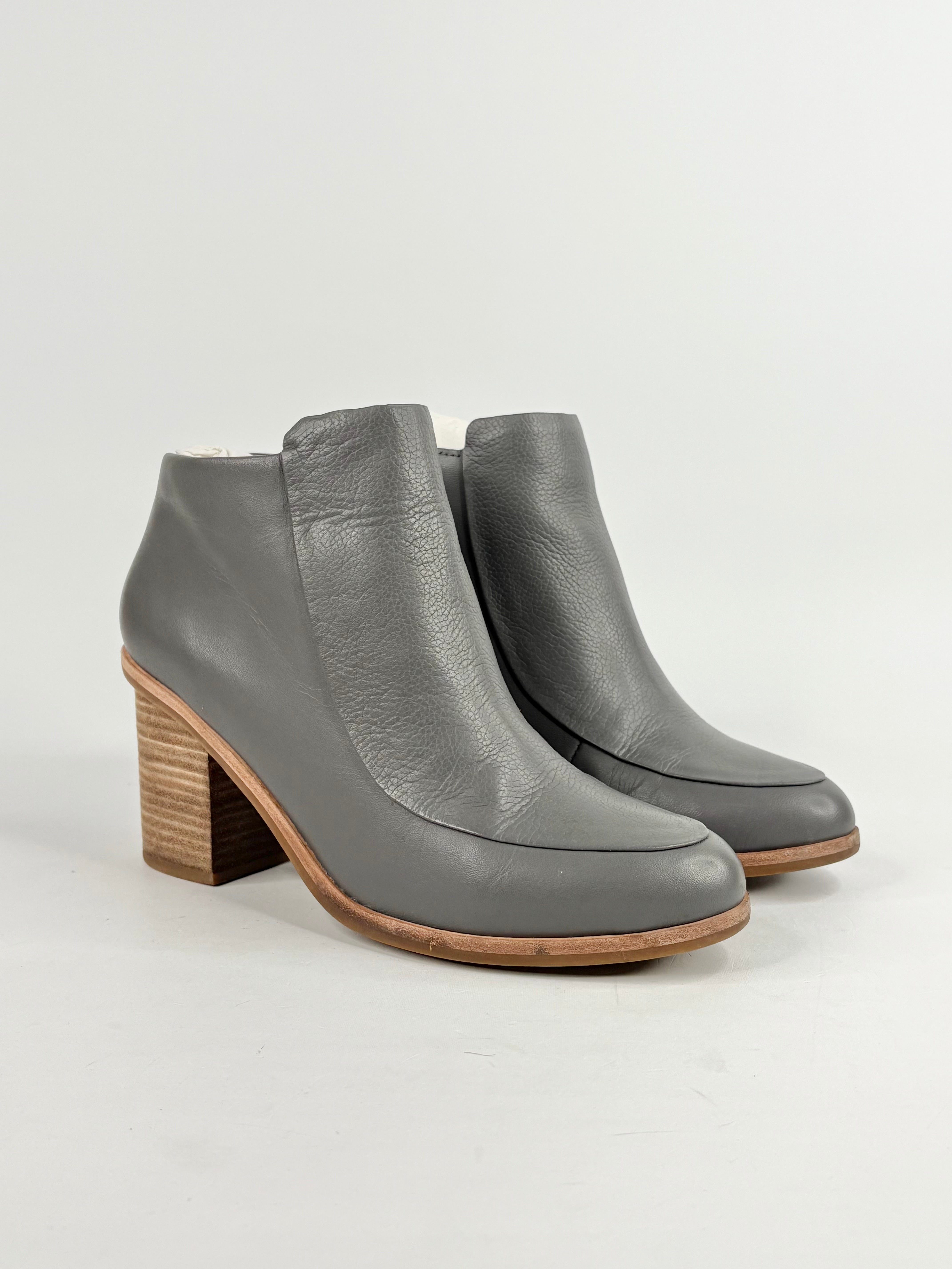 Pair of gray ankle boots with wooden heel on a light gray background