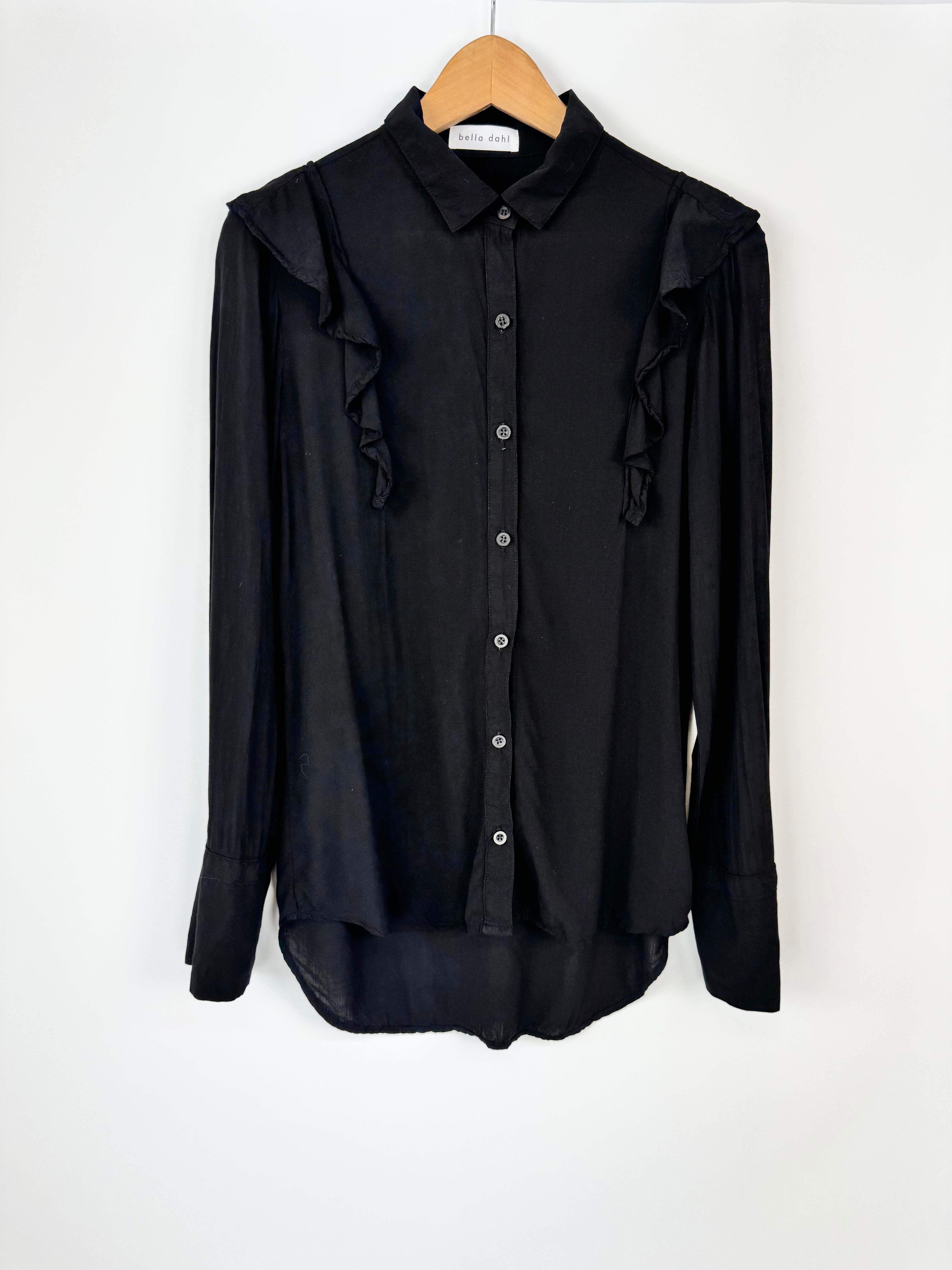 Black shirt with ruffled sleeves on a wooden hanger against a white background