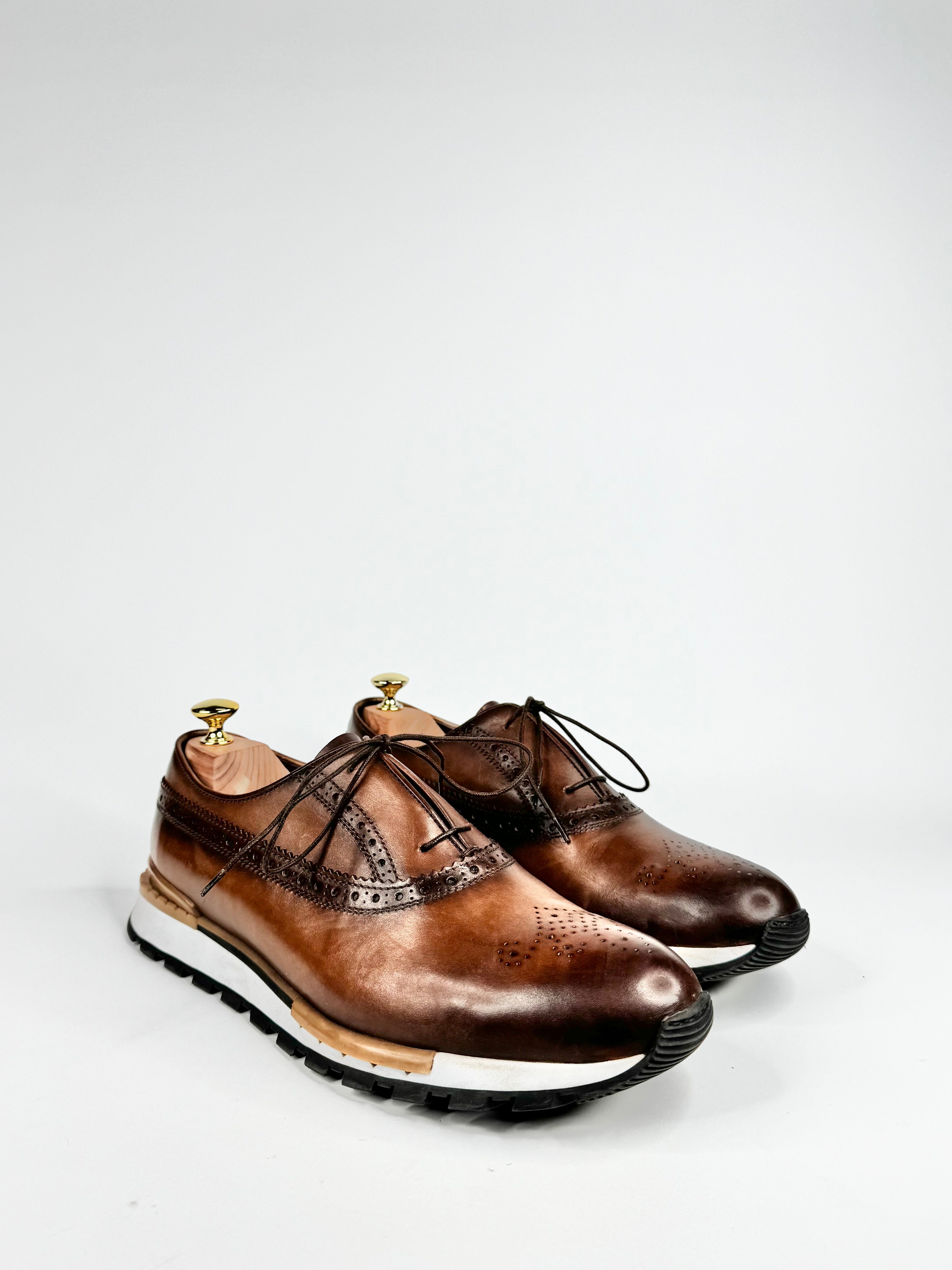 Pair of brown leather shoes with black laces on a white background