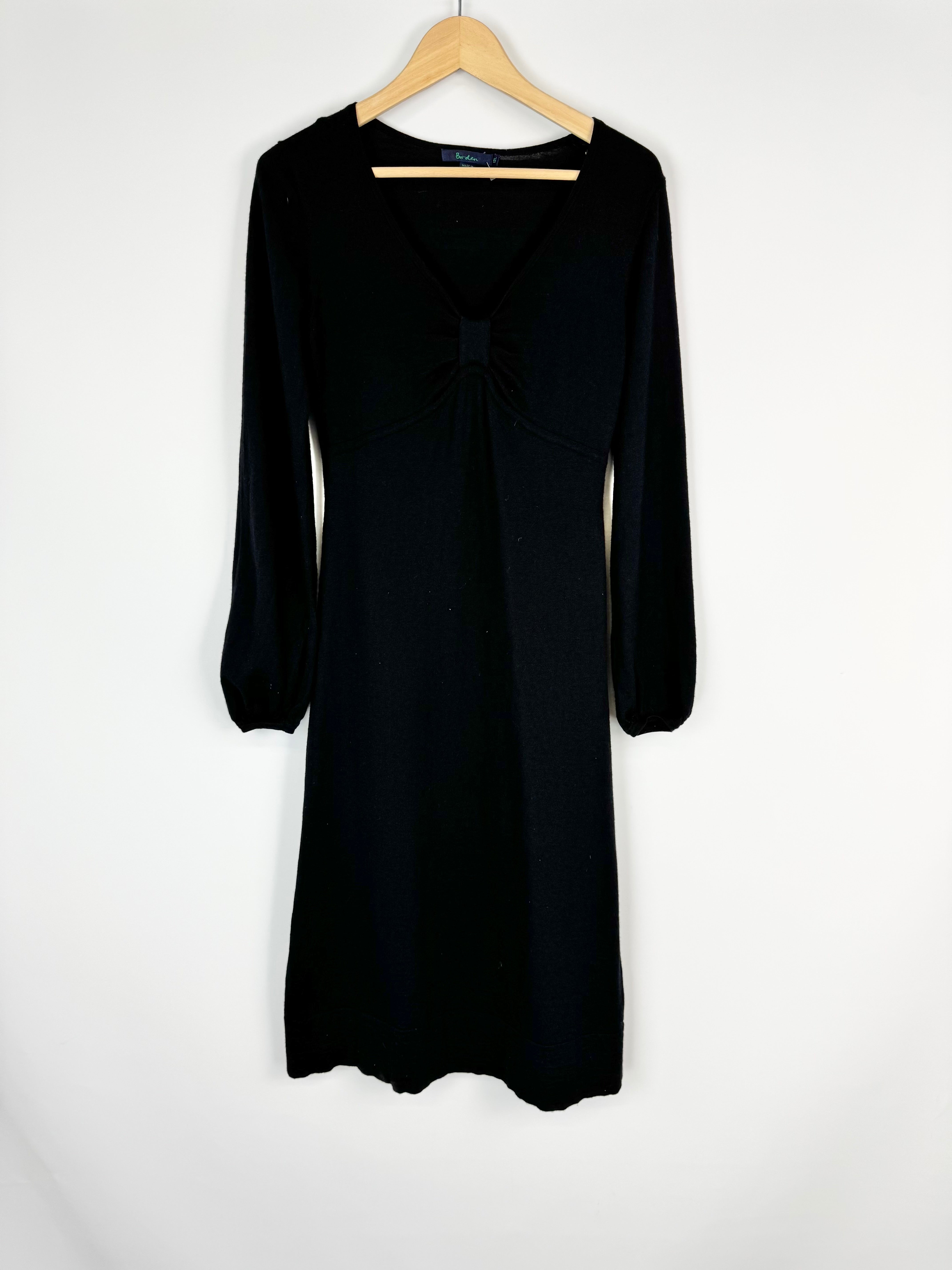 Black dress on a wooden hanger against a white background