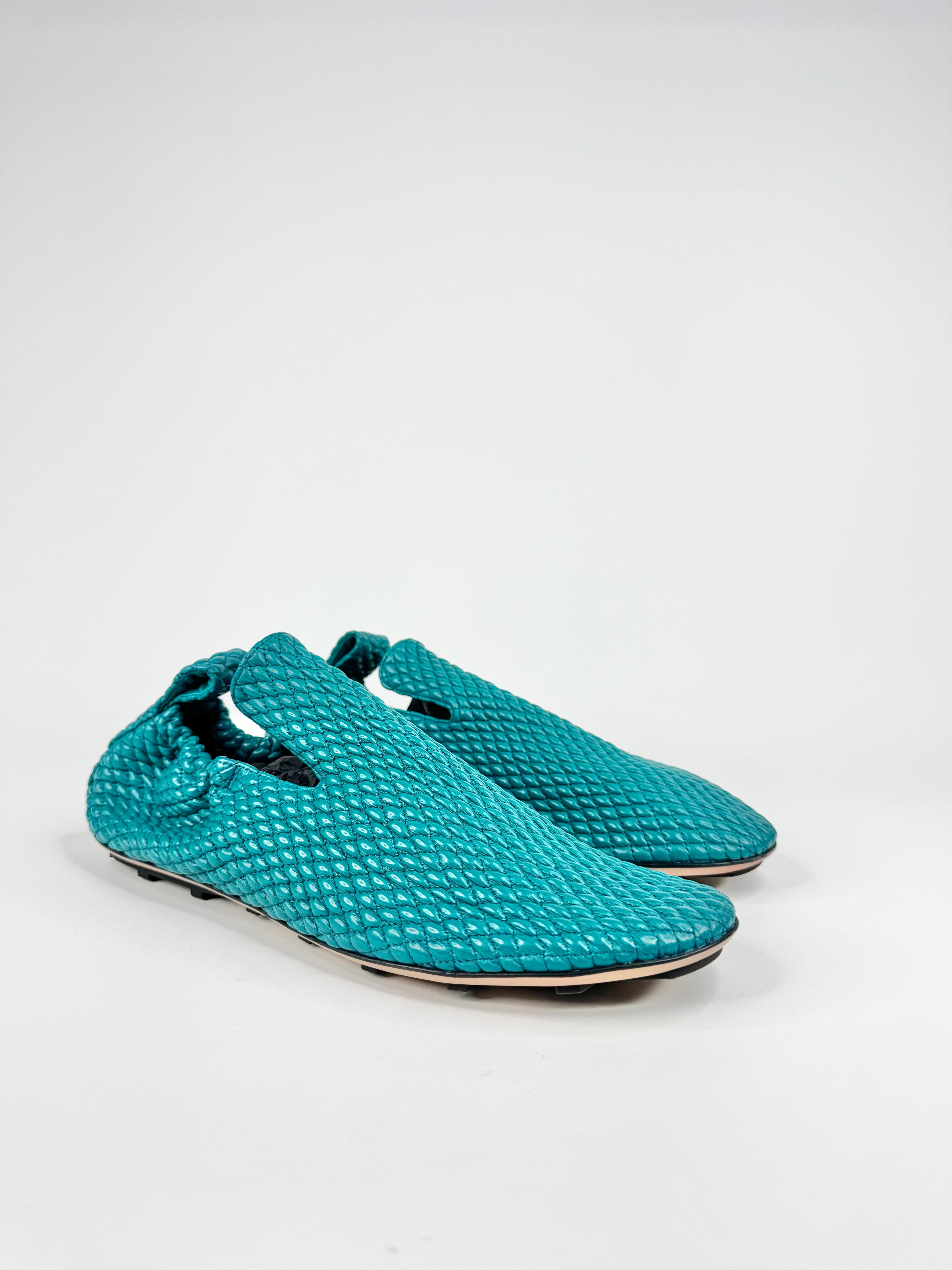 Pair of teal textured slippers on a white background