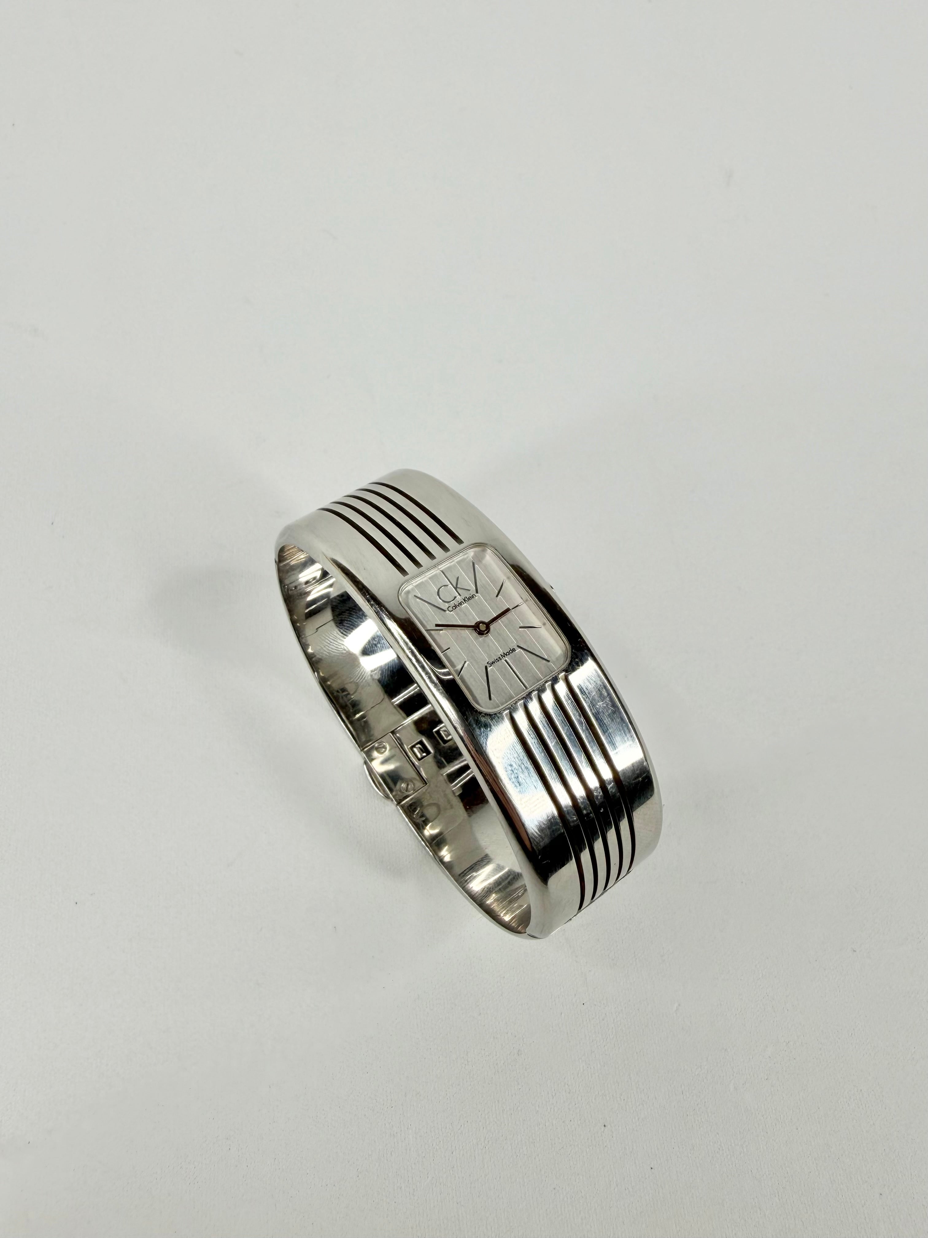 Silver ring with a clock face design on a light gray background