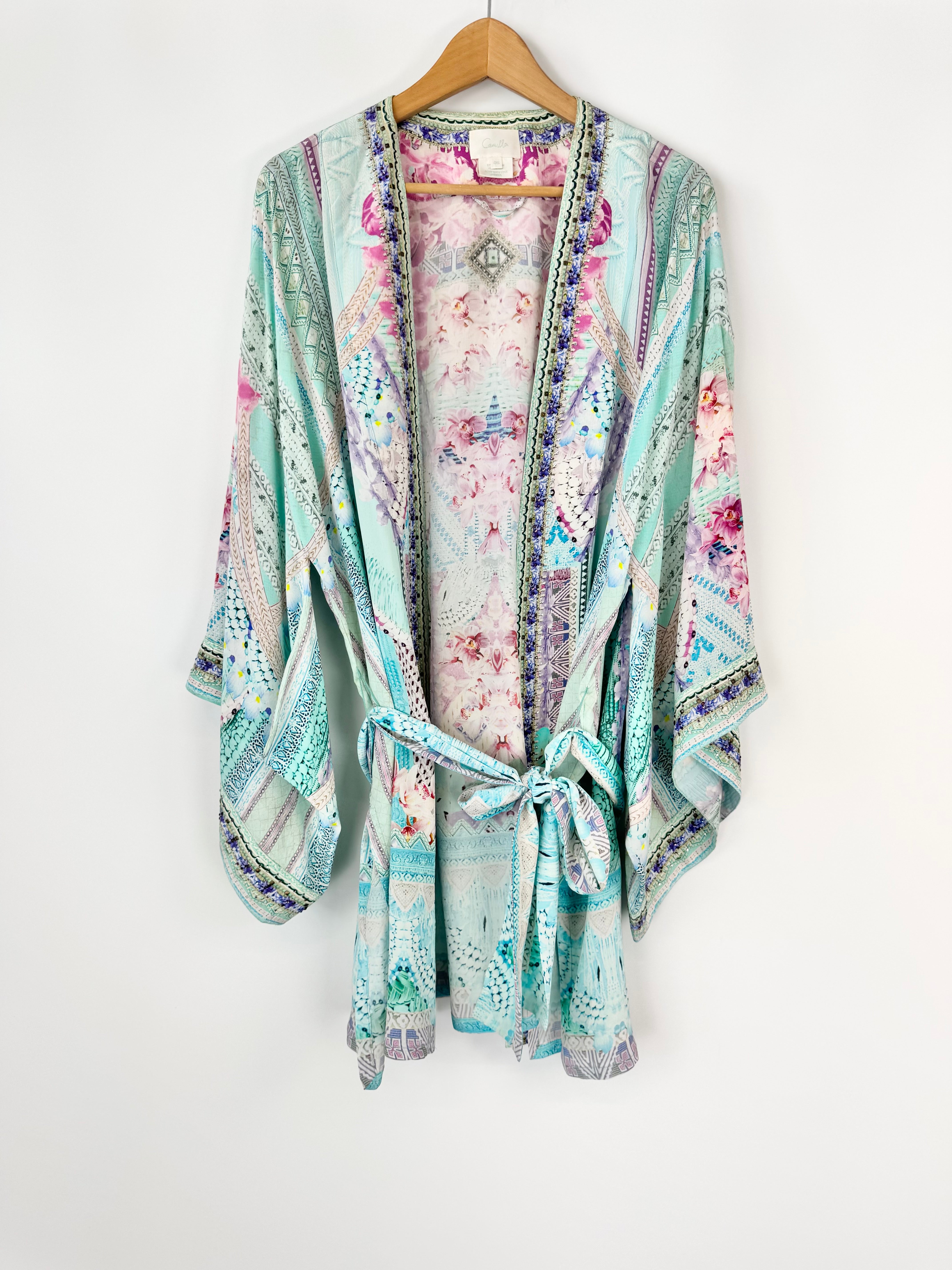Floral patterned kimono on a hanger against a white background