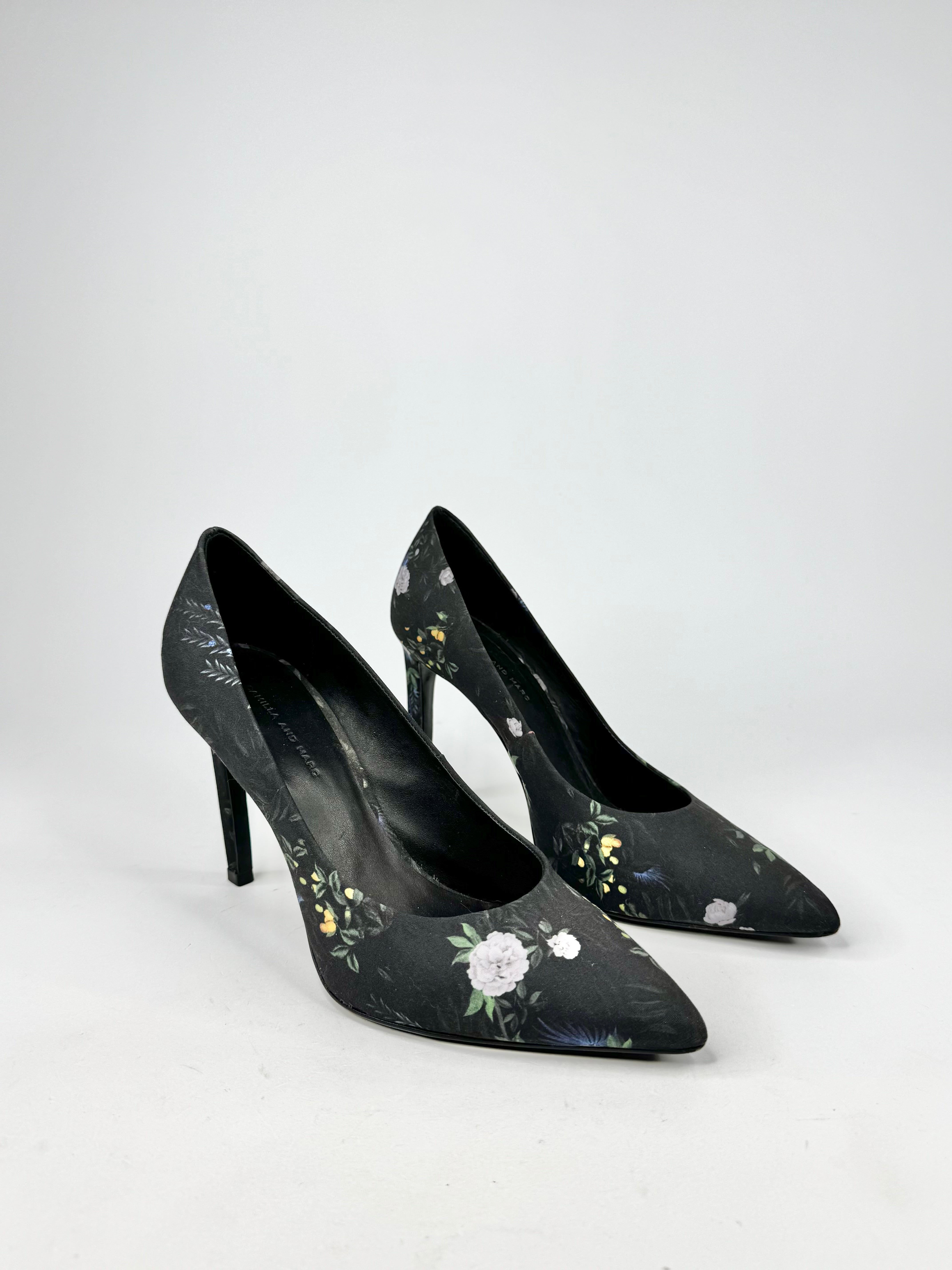 Black high-heeled shoes with floral designs on a white background