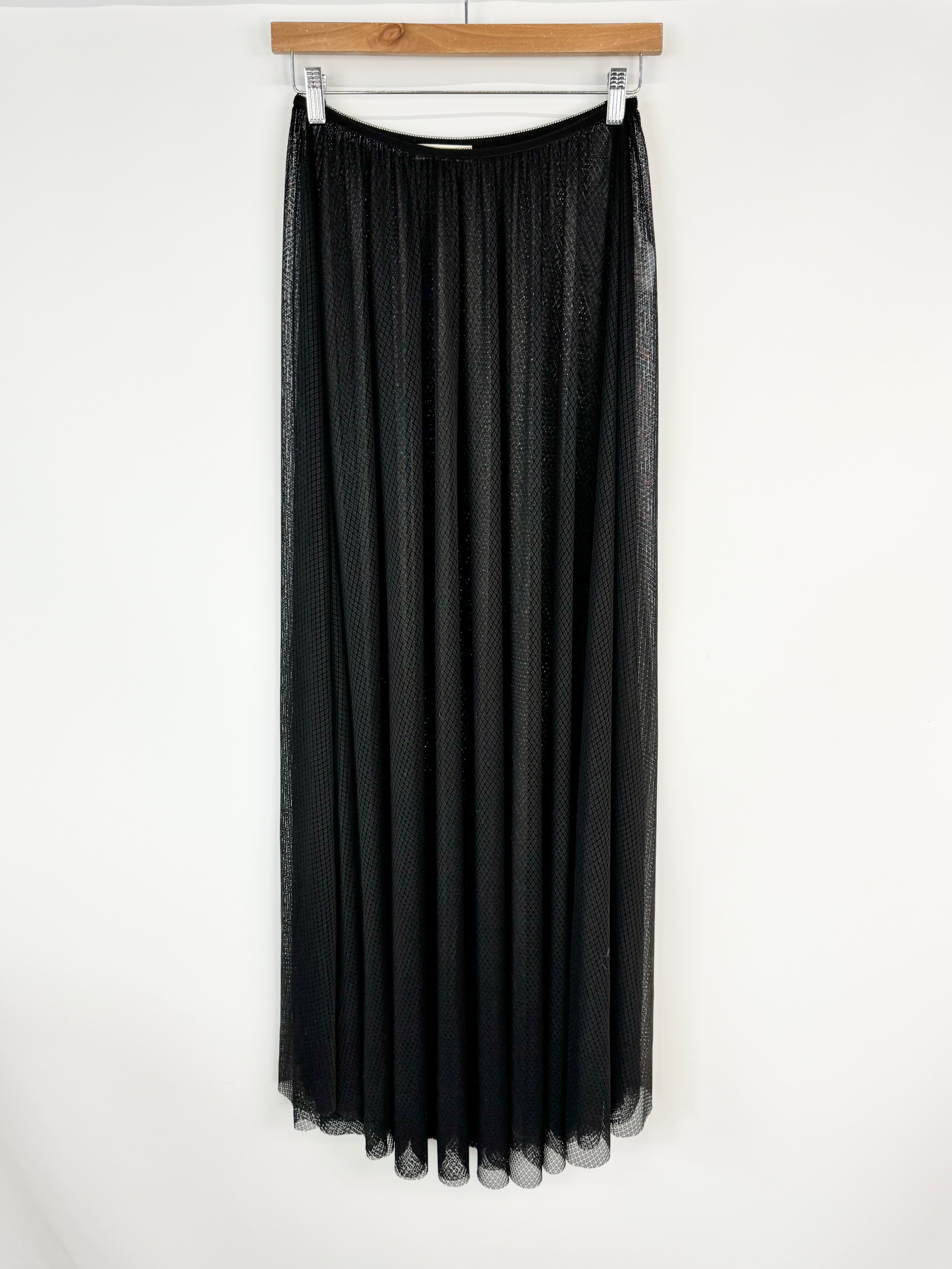 Black long skirt hanging on a wooden hanger against a white background