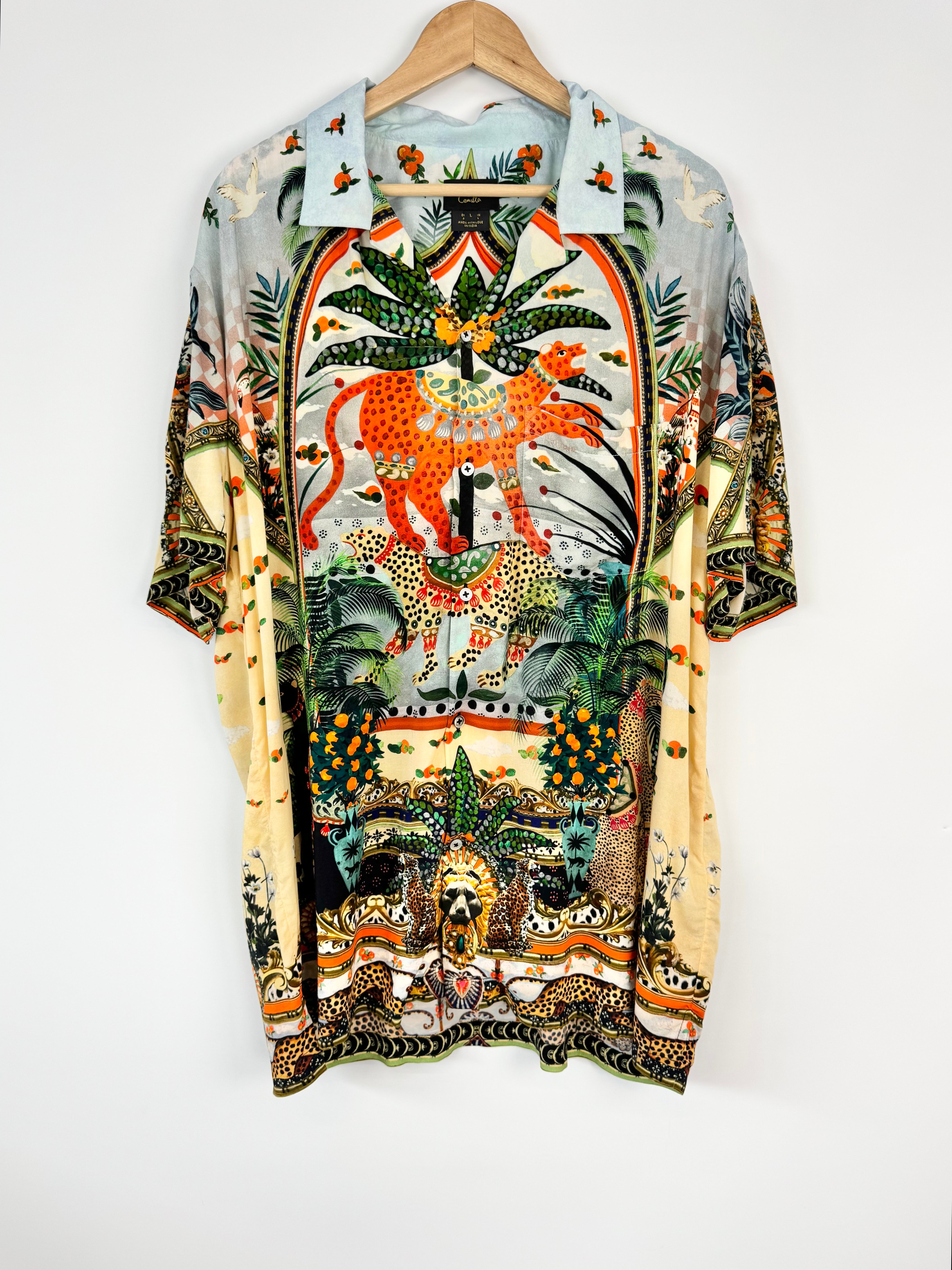 Colorful shirt with animal and nature design on a hanger against a white background