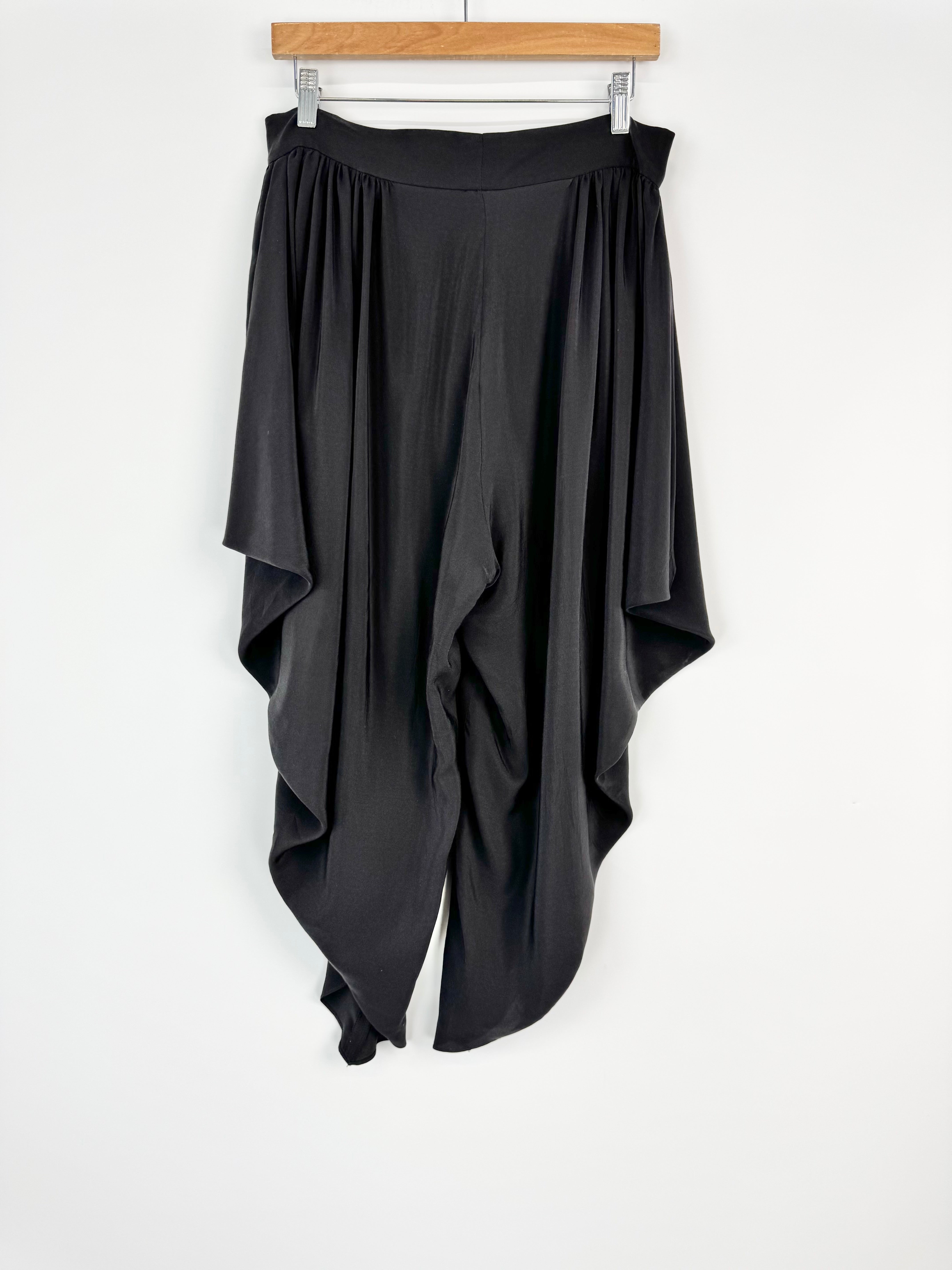 Black draped skirt on a hanger against a white background