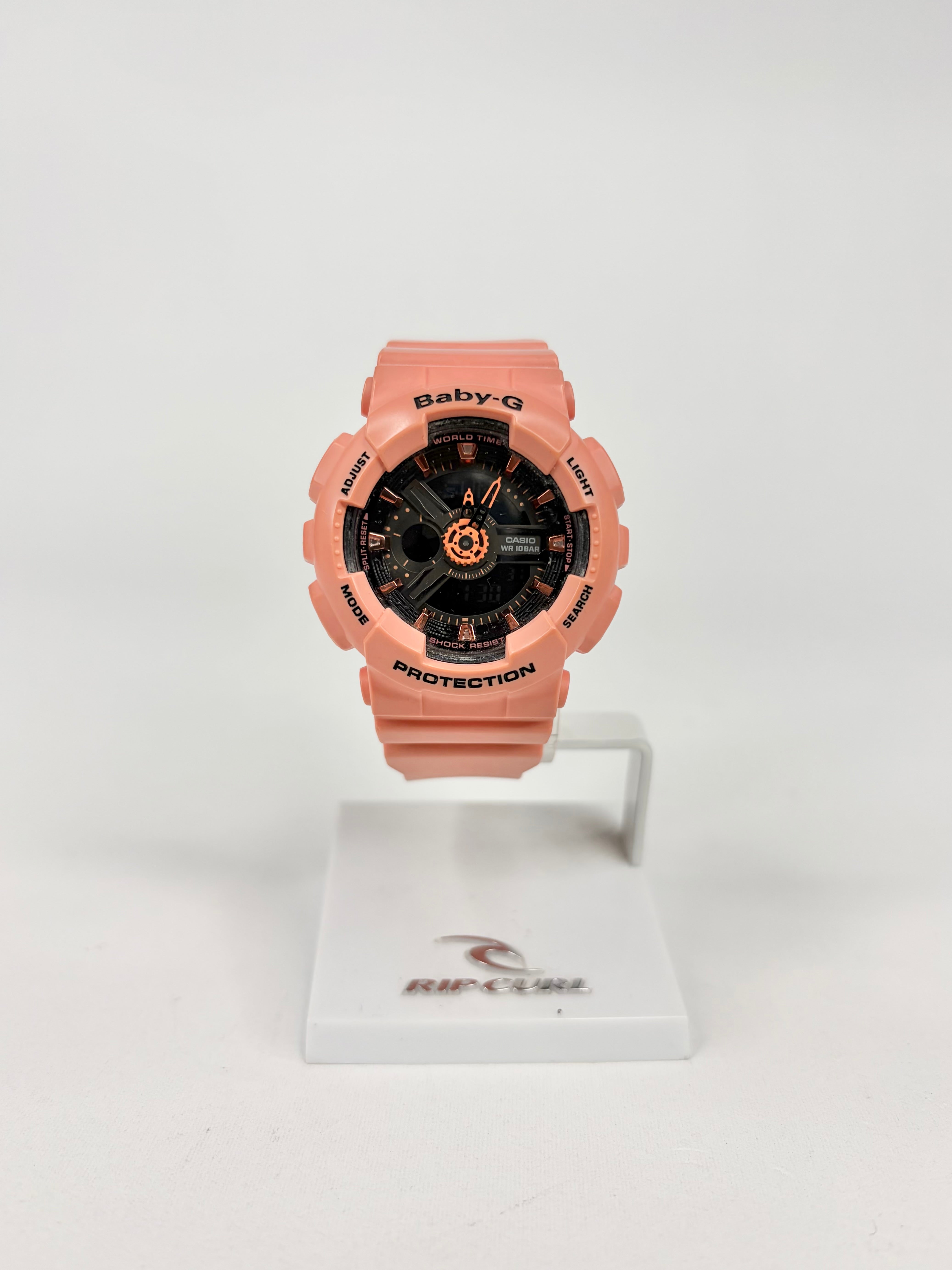 Pink watch with black face on a white stand