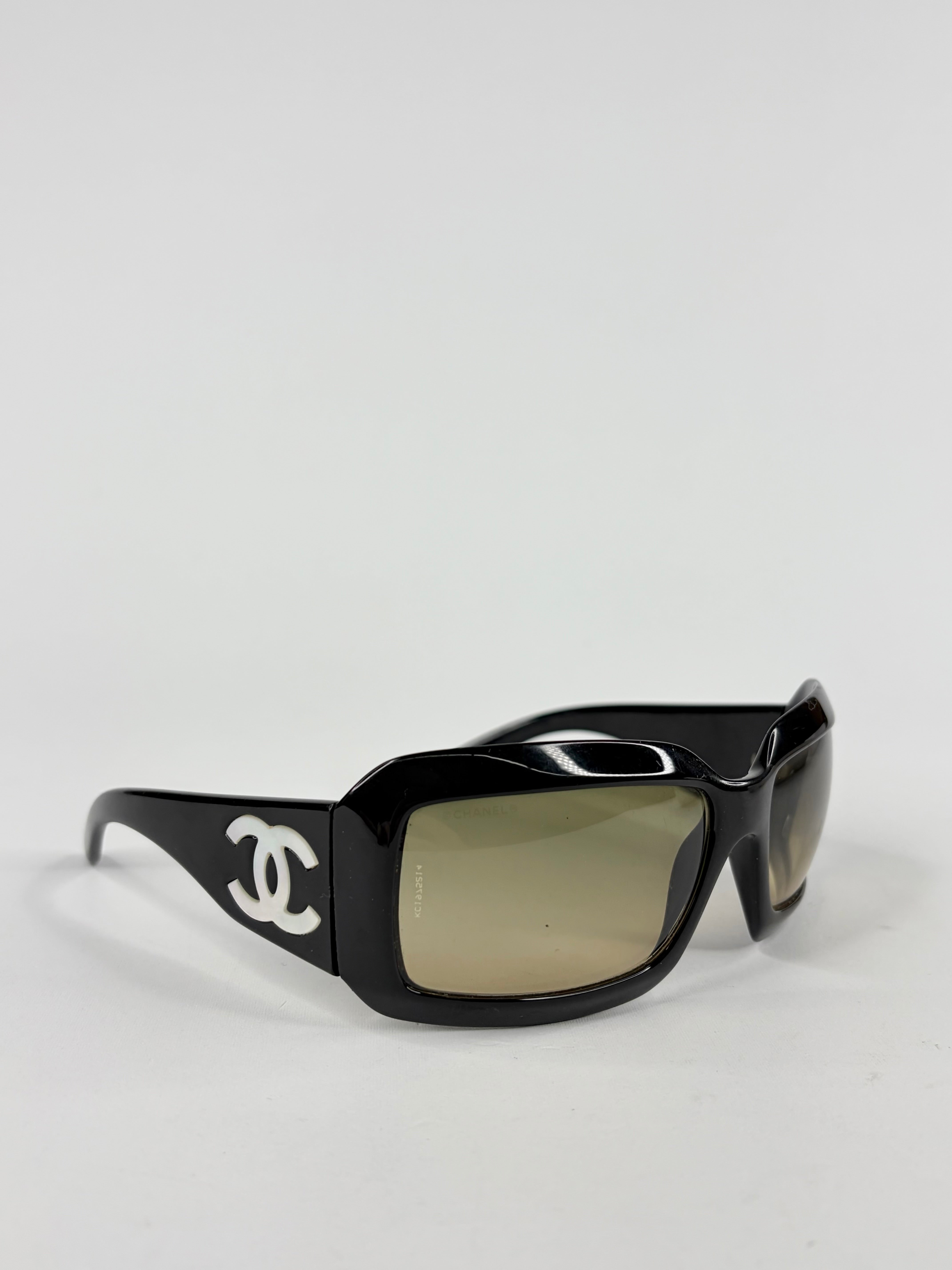 Black sunglasses with a logo on a light gray background