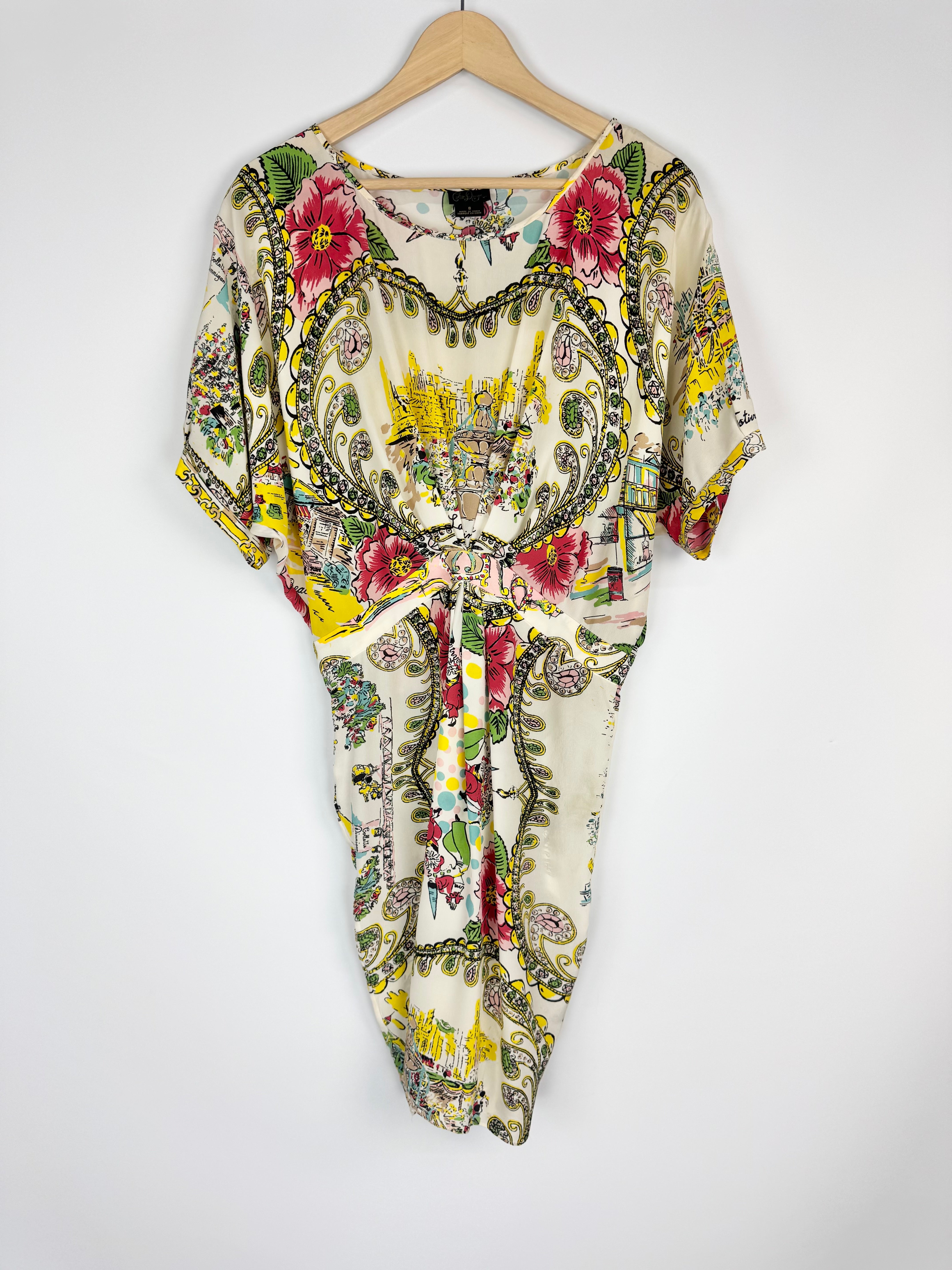 Colorful patterned dress on a wooden hanger against a white background