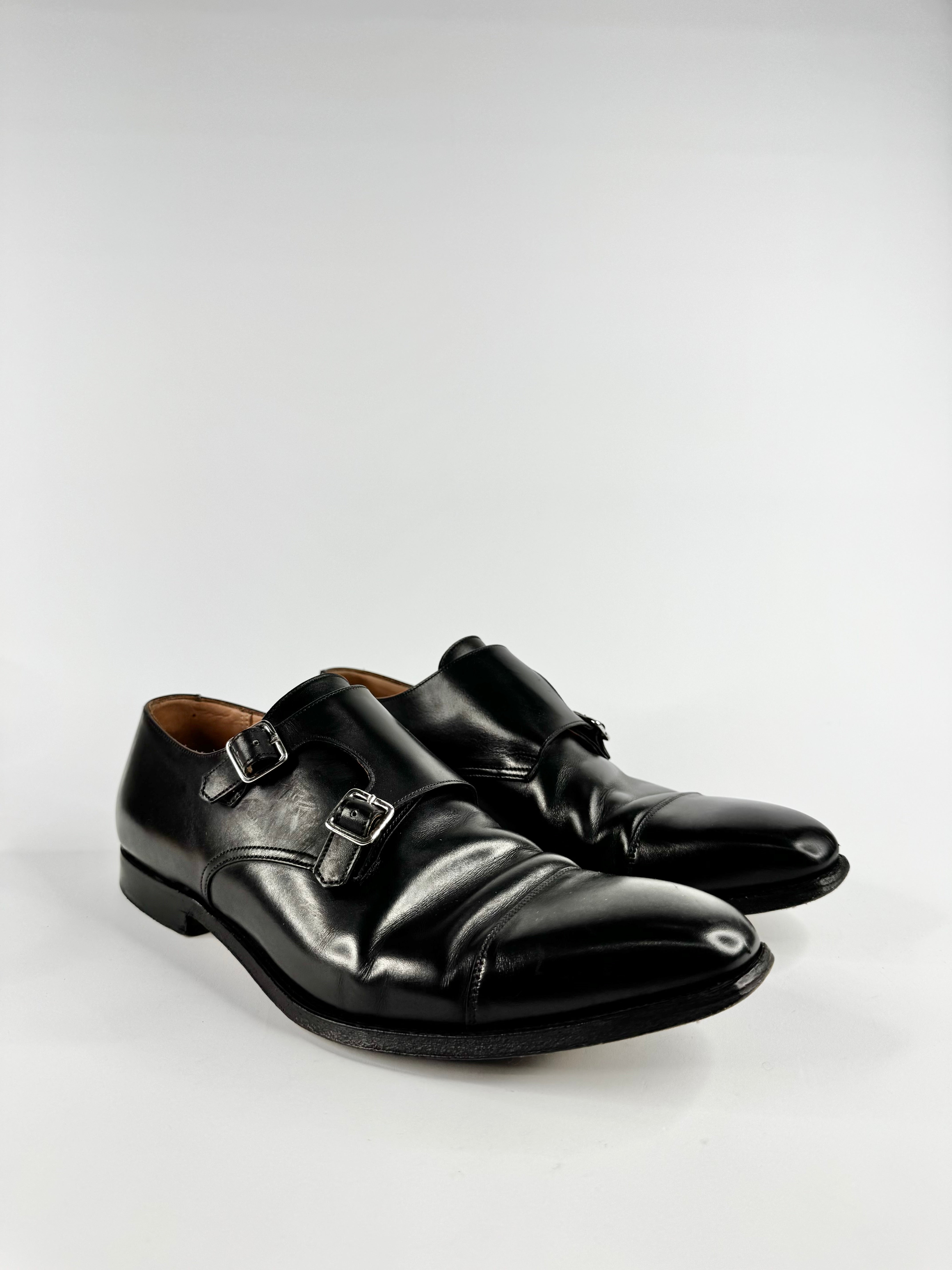 Pair of black leather shoes with buckles on a light gray background