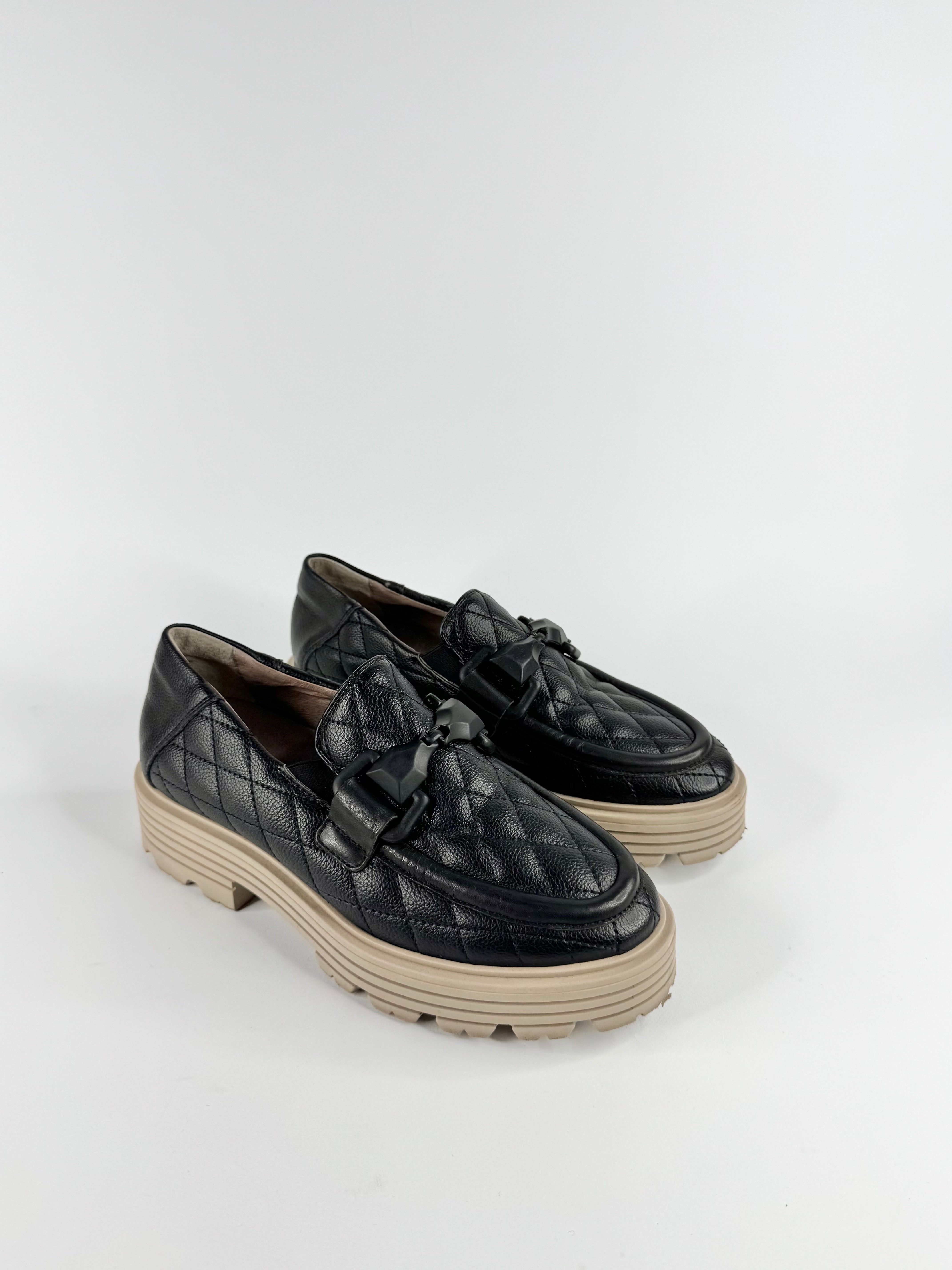 Black quilted loafers on a white background