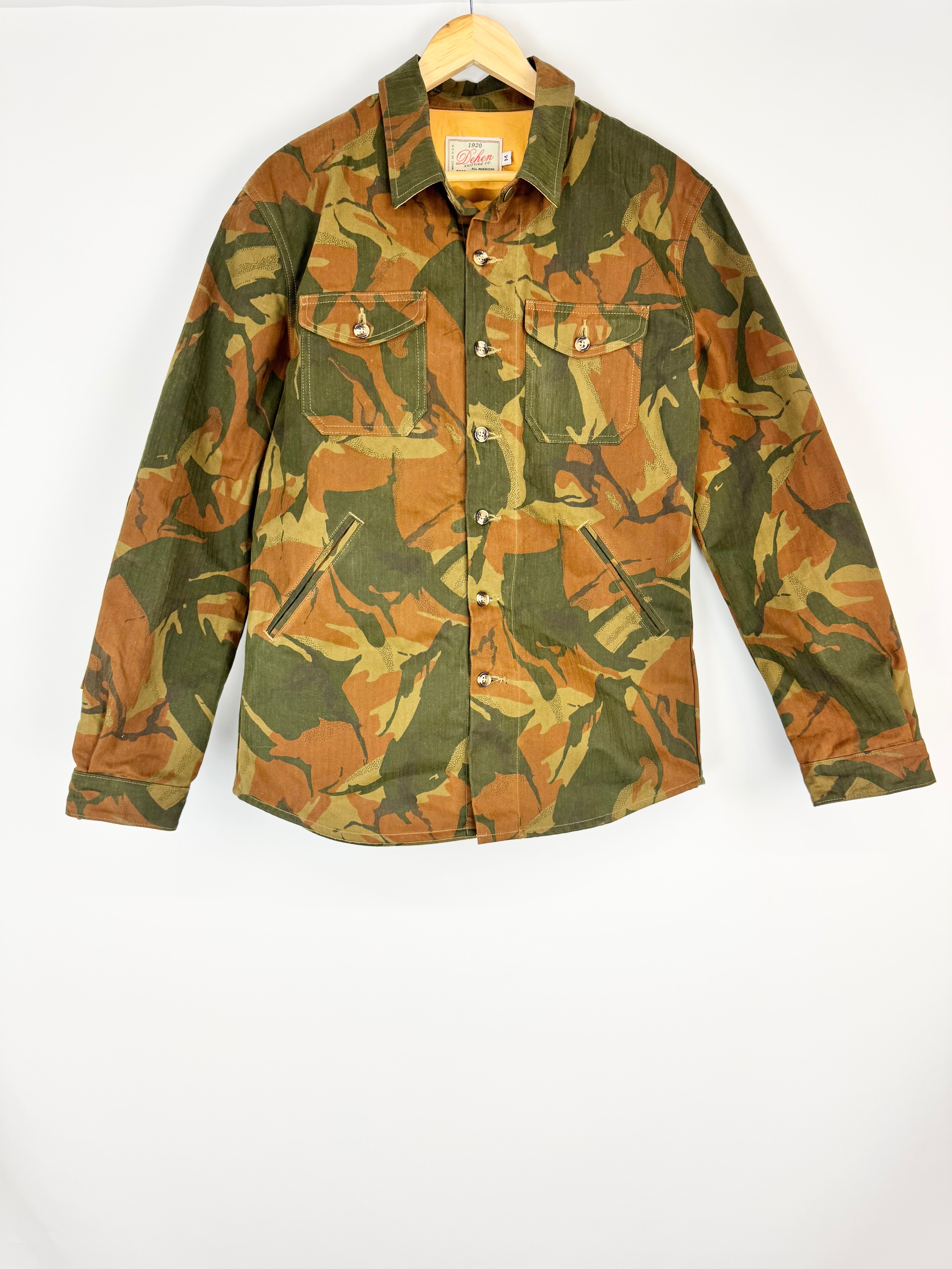 Camouflage-patterned shirt on a hanger against a white background