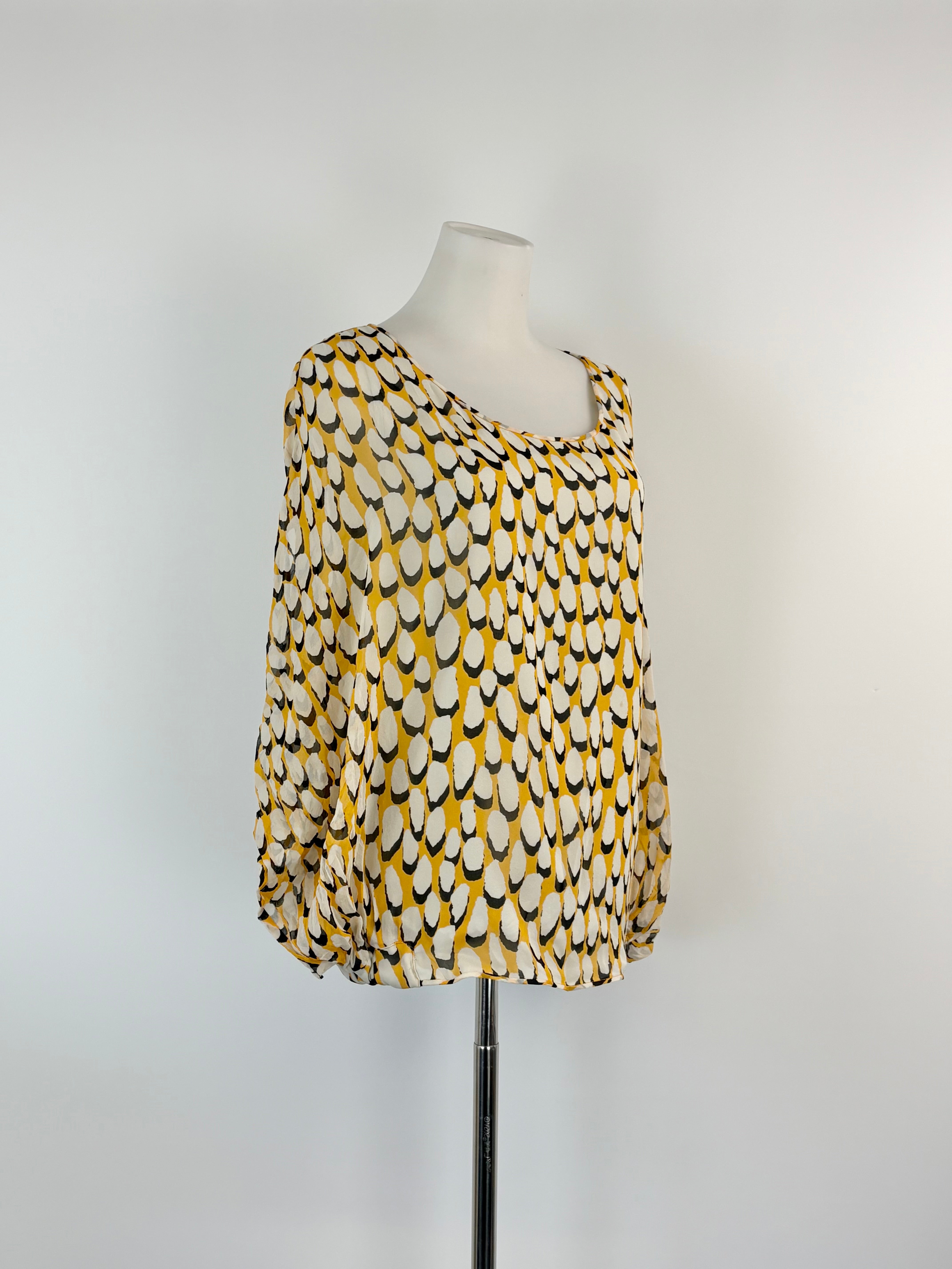 Yellow and black patterned top on a mannequin against a white background