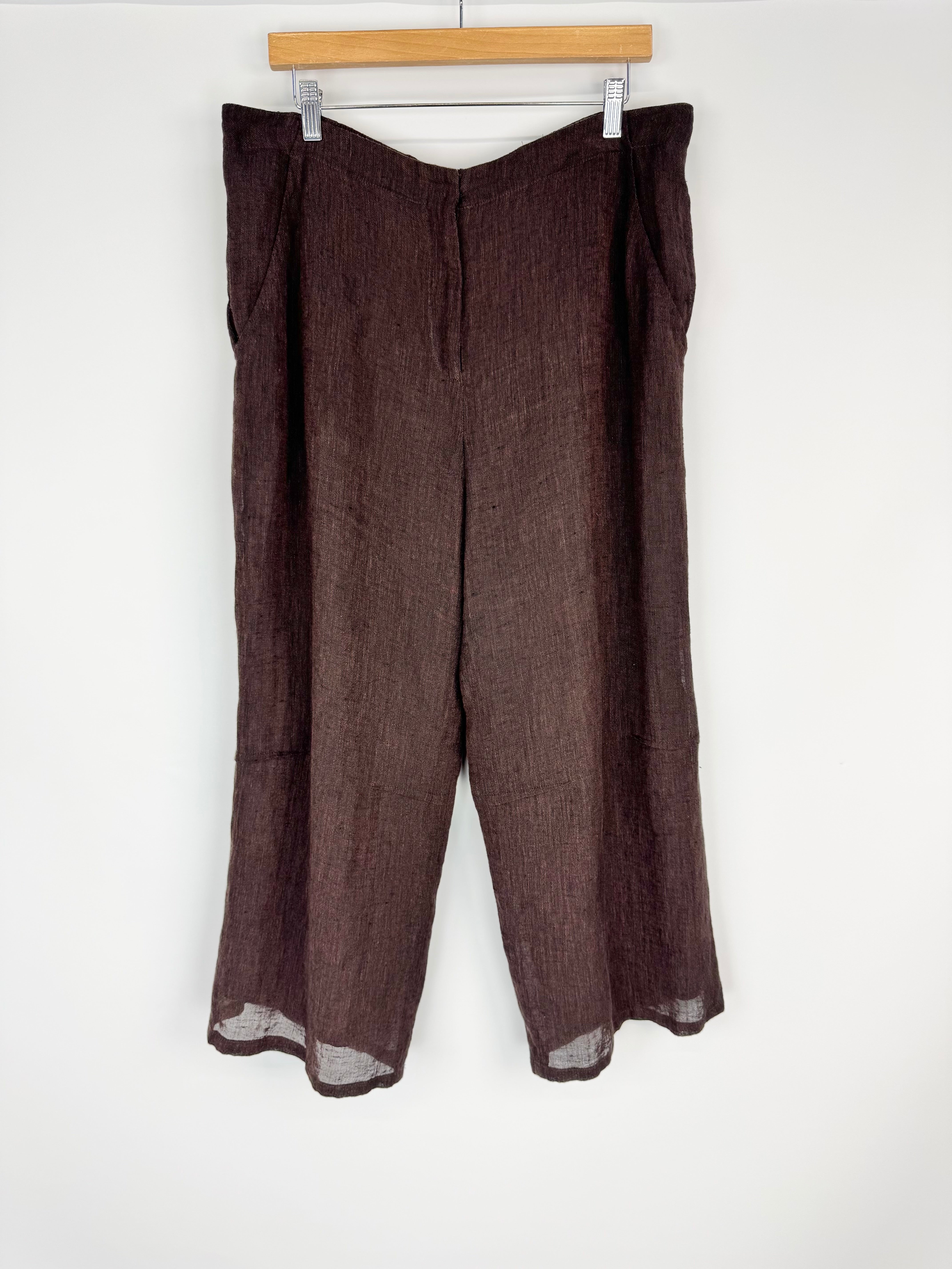 Brown pants hanging on a wooden hanger against a white background