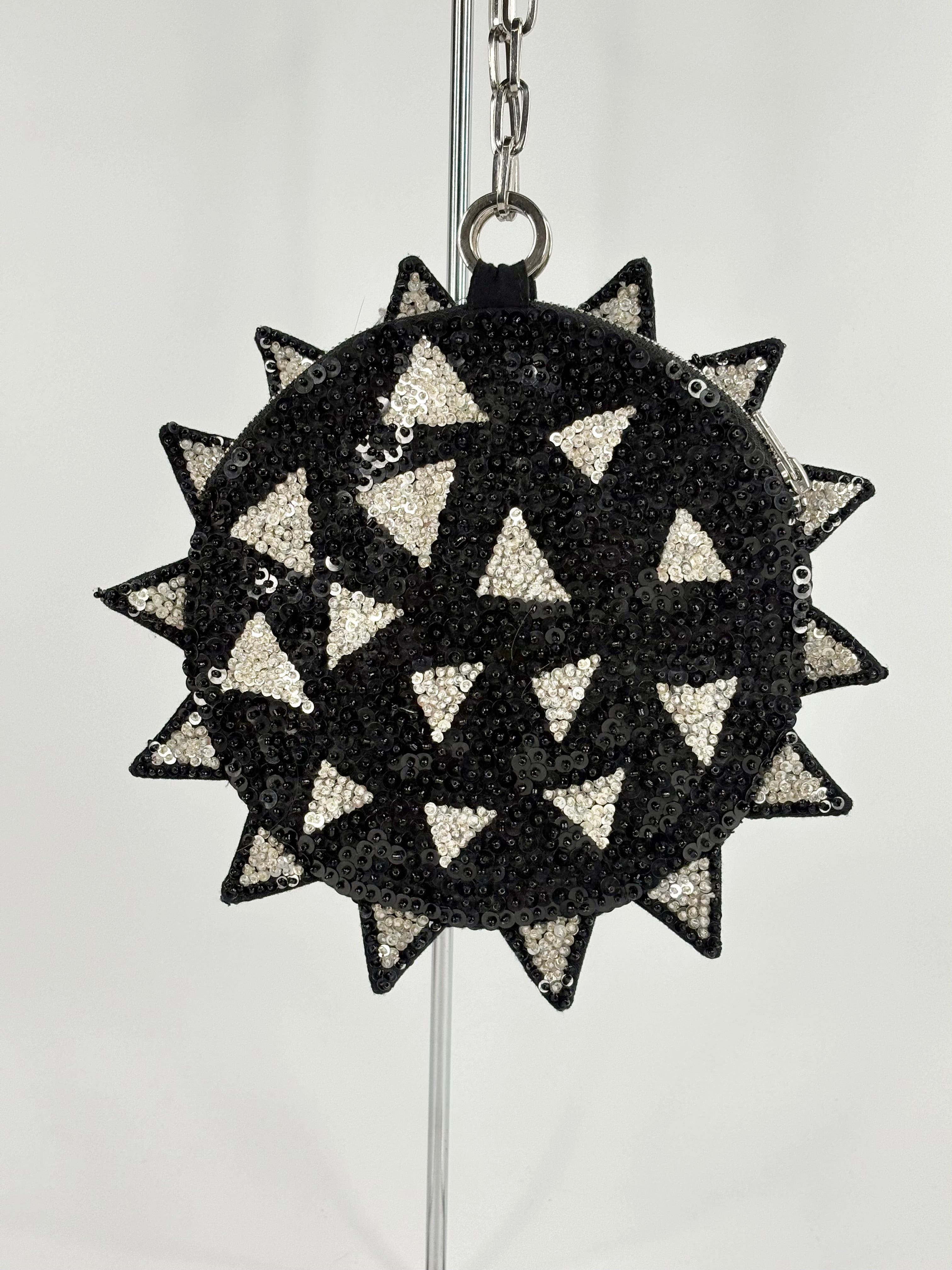 Black and white geometric patterned bag with chain strap on a light gray background