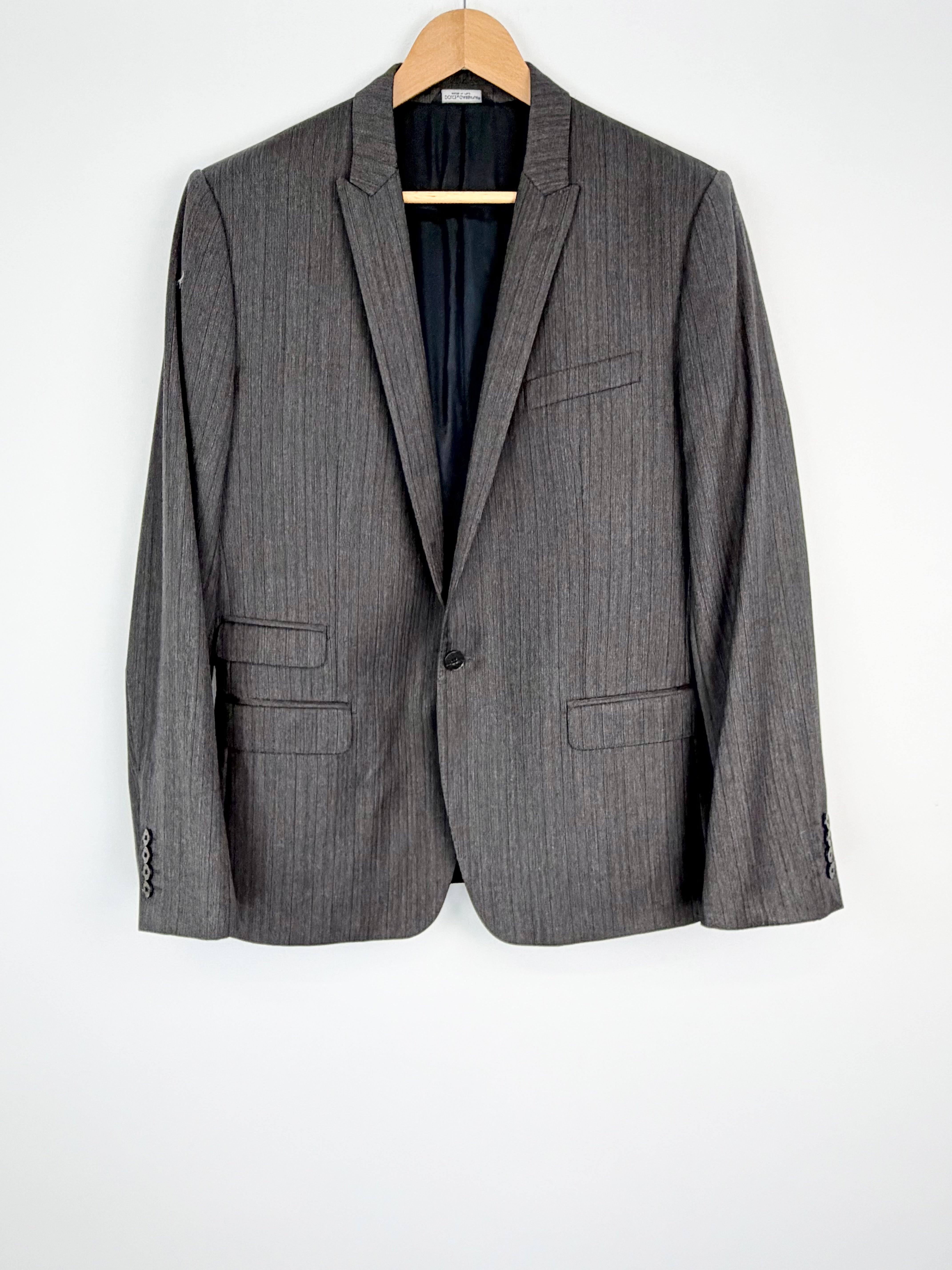 Gray pinstripe blazer on a hanger against a white background