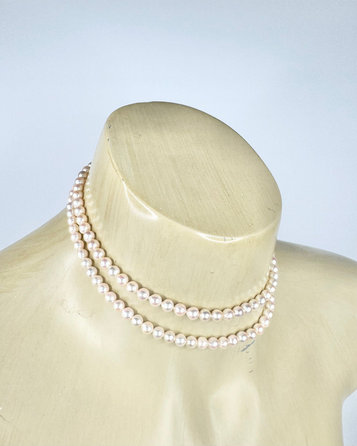 Pearl necklace on a mannequin head against a light background