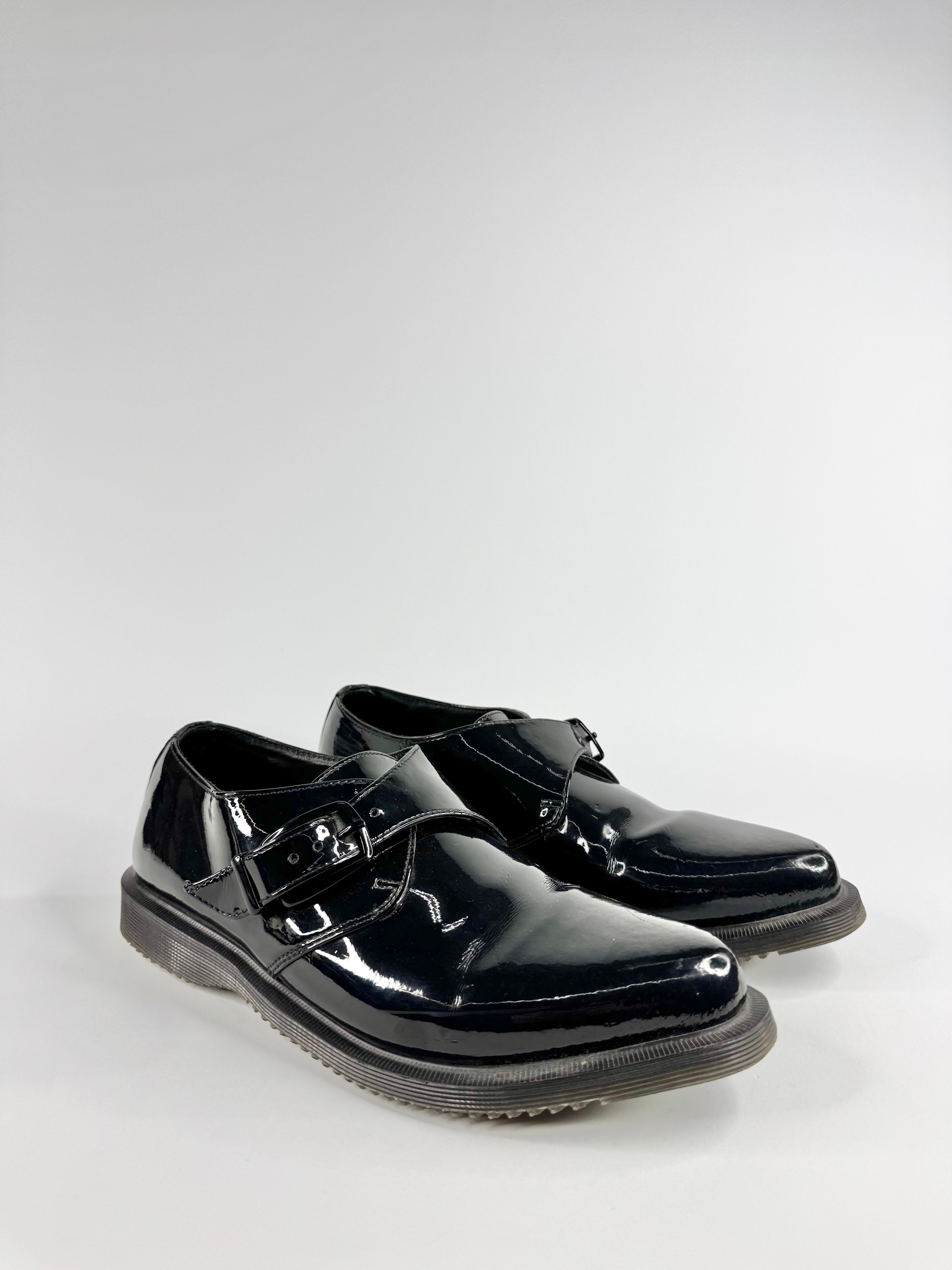 Black patent leather shoes with buckles on a white background