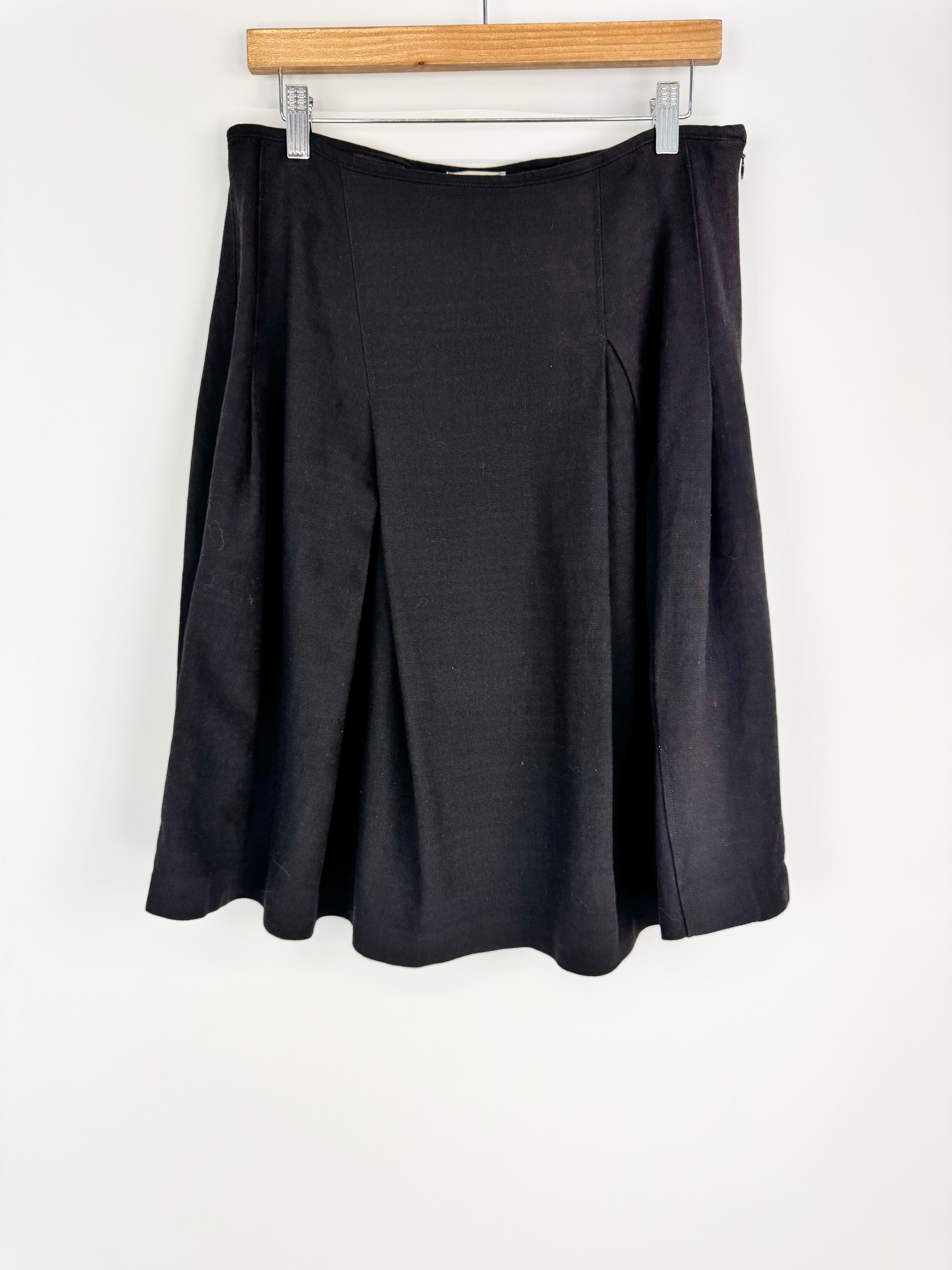 Black skirt hanging on a wooden hanger against a white background