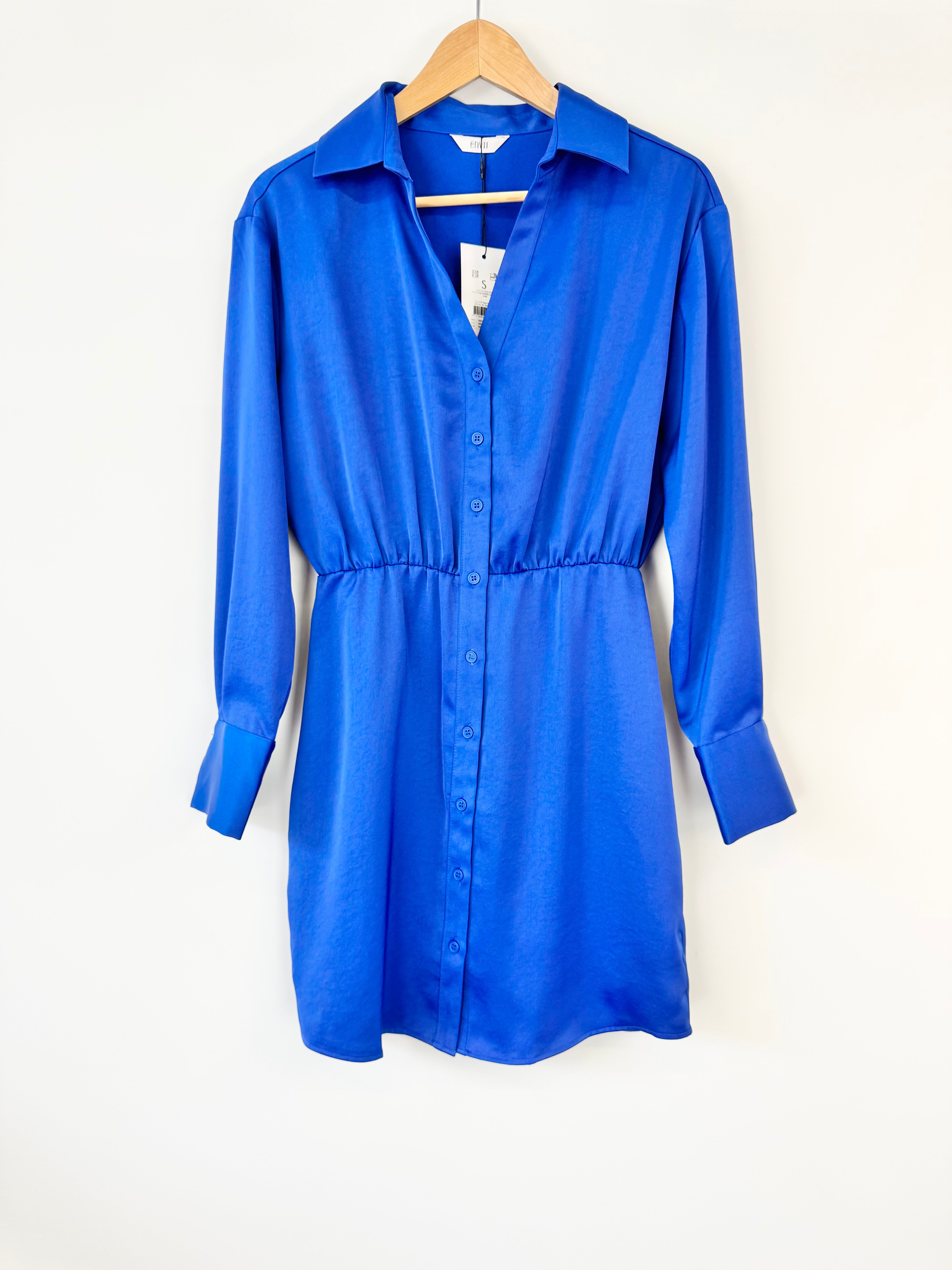 Blue shirt dress on a hanger against a white background