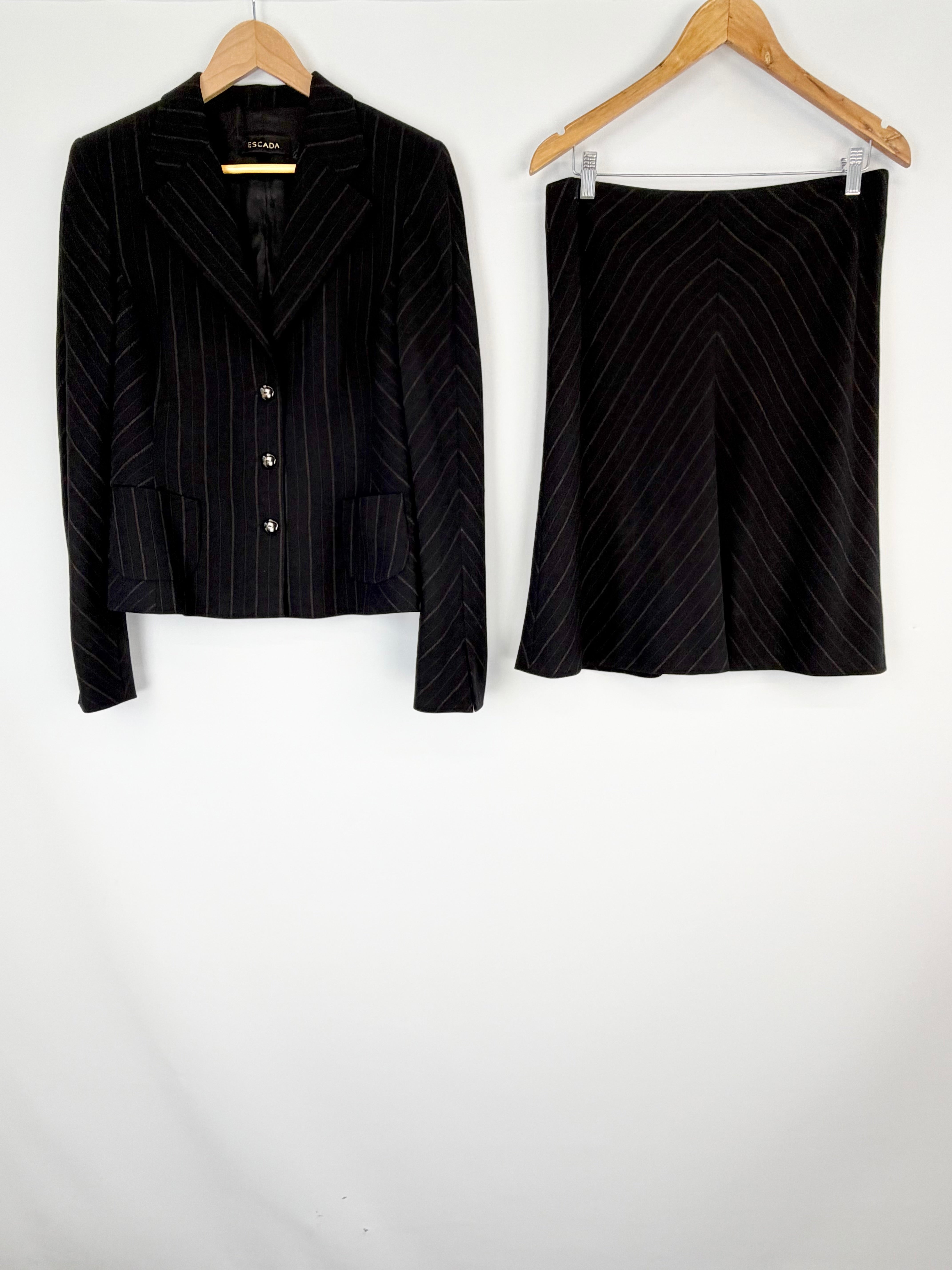 Black pinstripe suit jacket and skirt on hangers against a white background