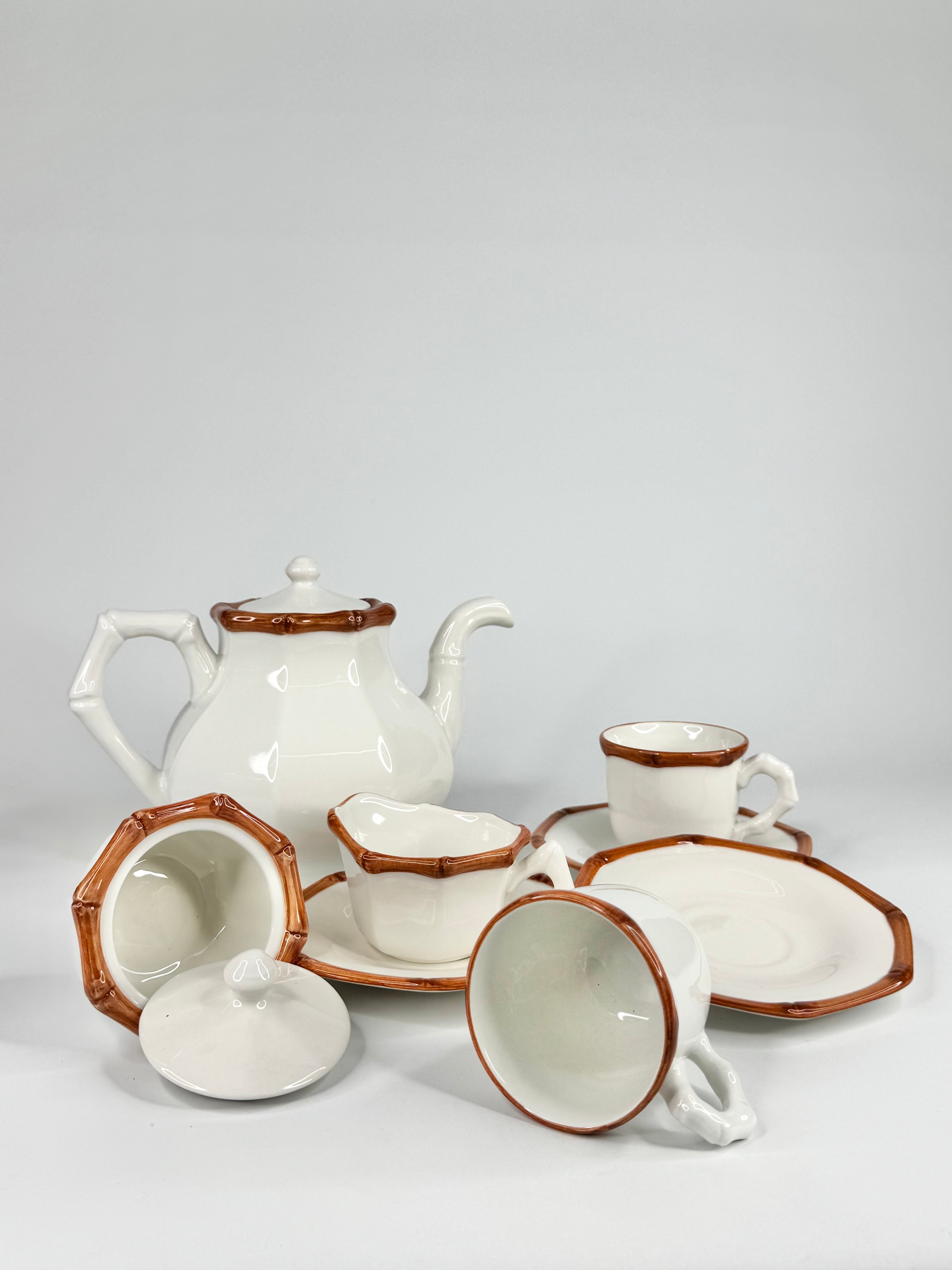 Ceramic tea set with white teapot, cups, and saucers on a gray background