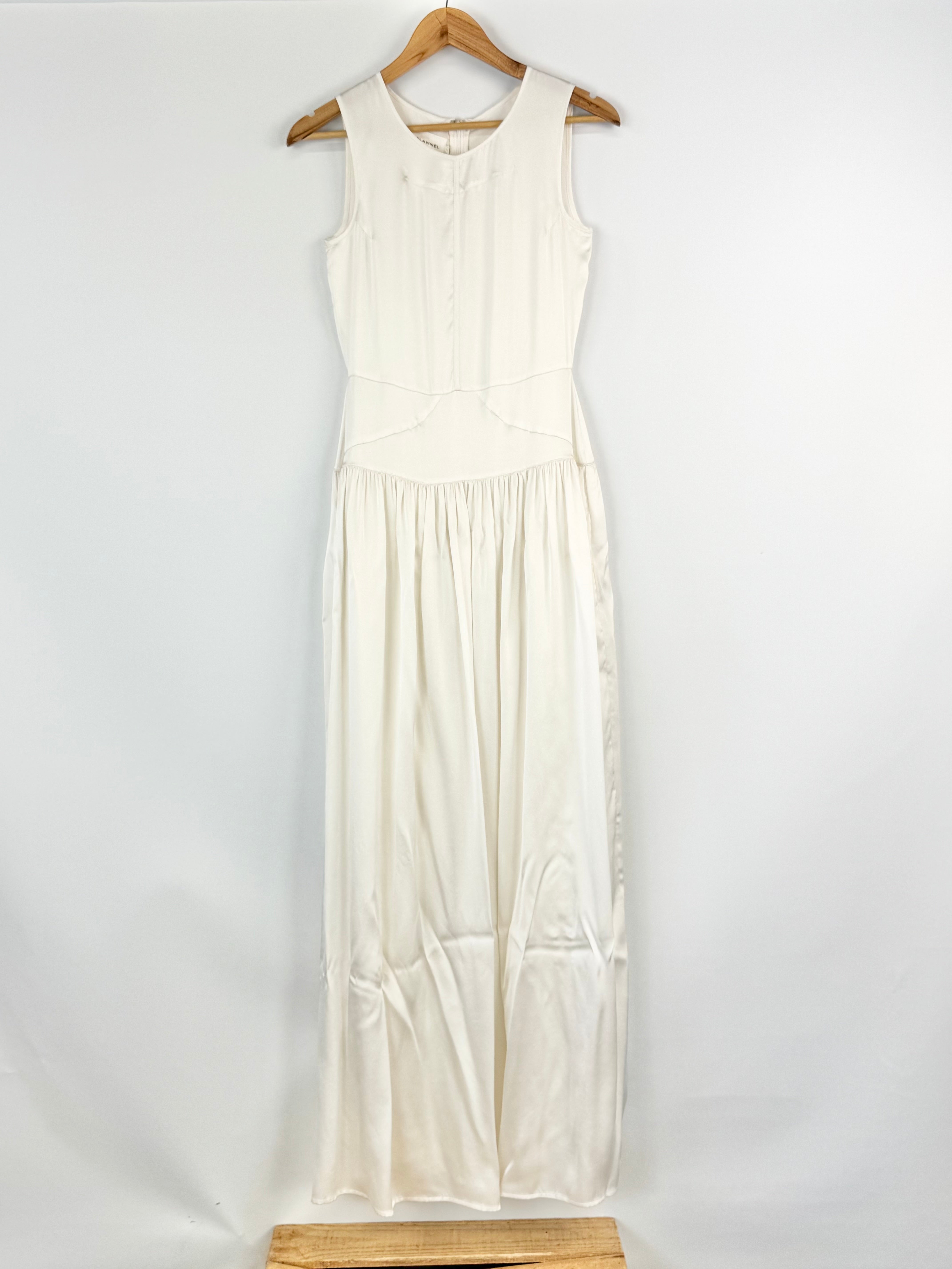 White sleeveless dress on a wooden hanger against a white background