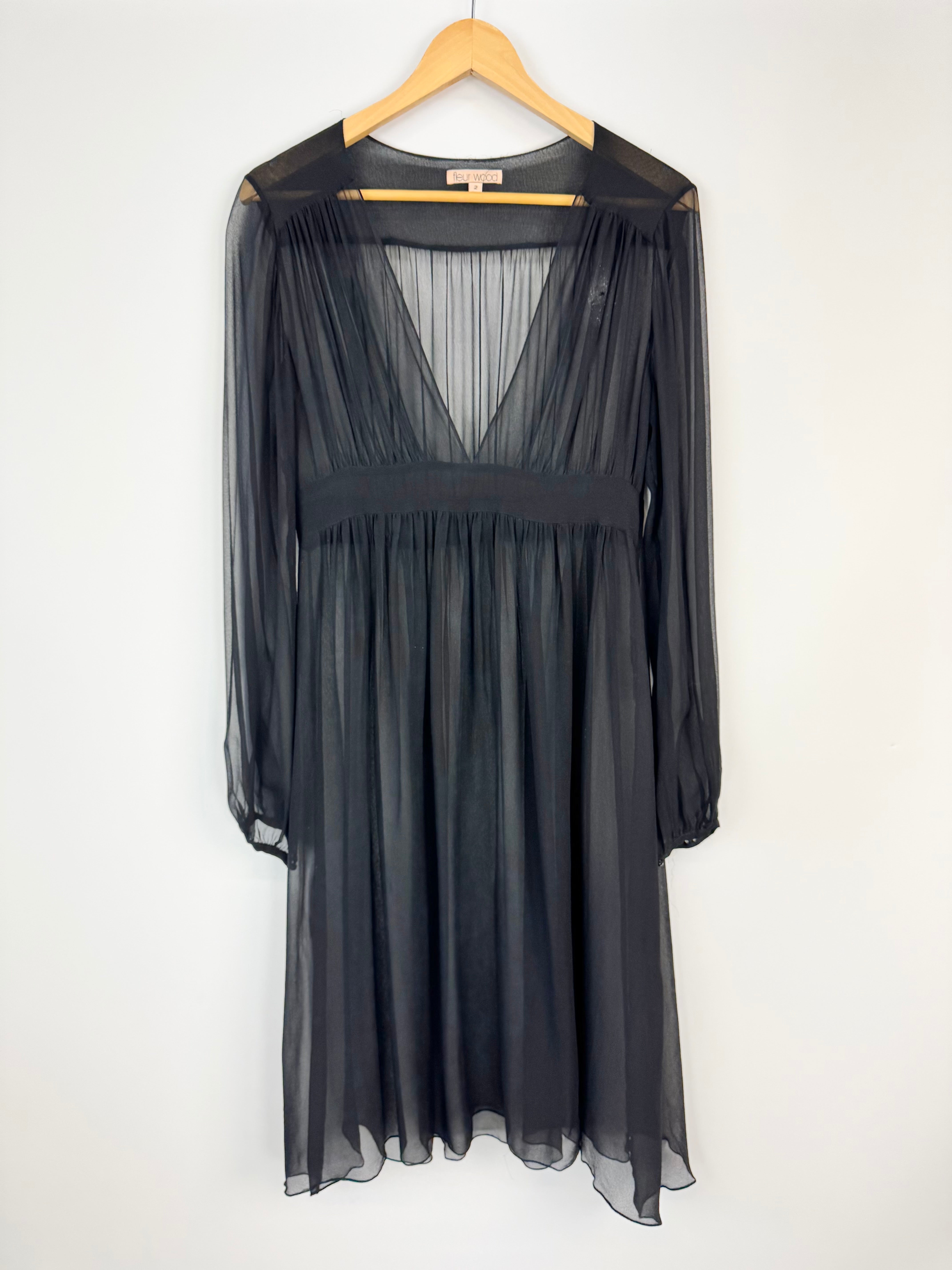 Black sheer dress on a wooden hanger against a white background