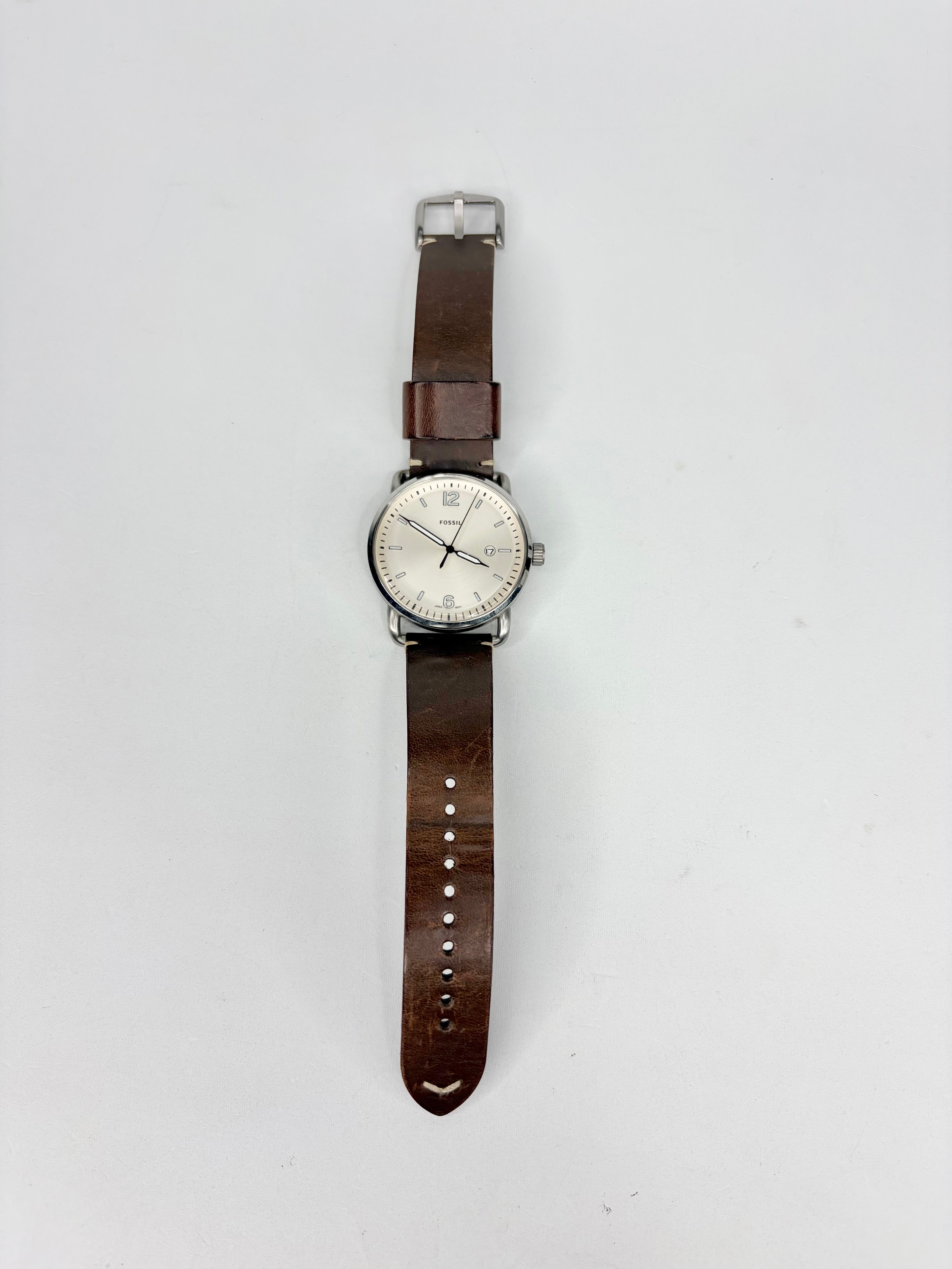 A round watch with brown leather strap against a white background